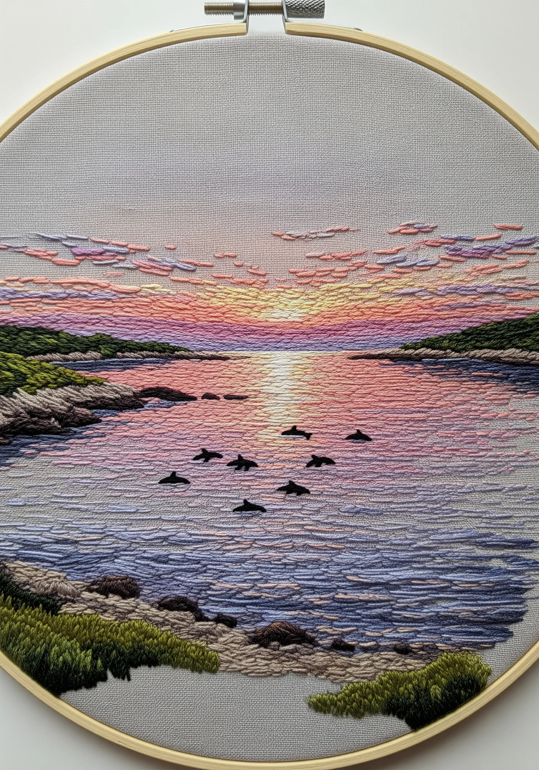 An impressionistic embroidery of a sunset over the ocean, with dolphins swimming in the distance.