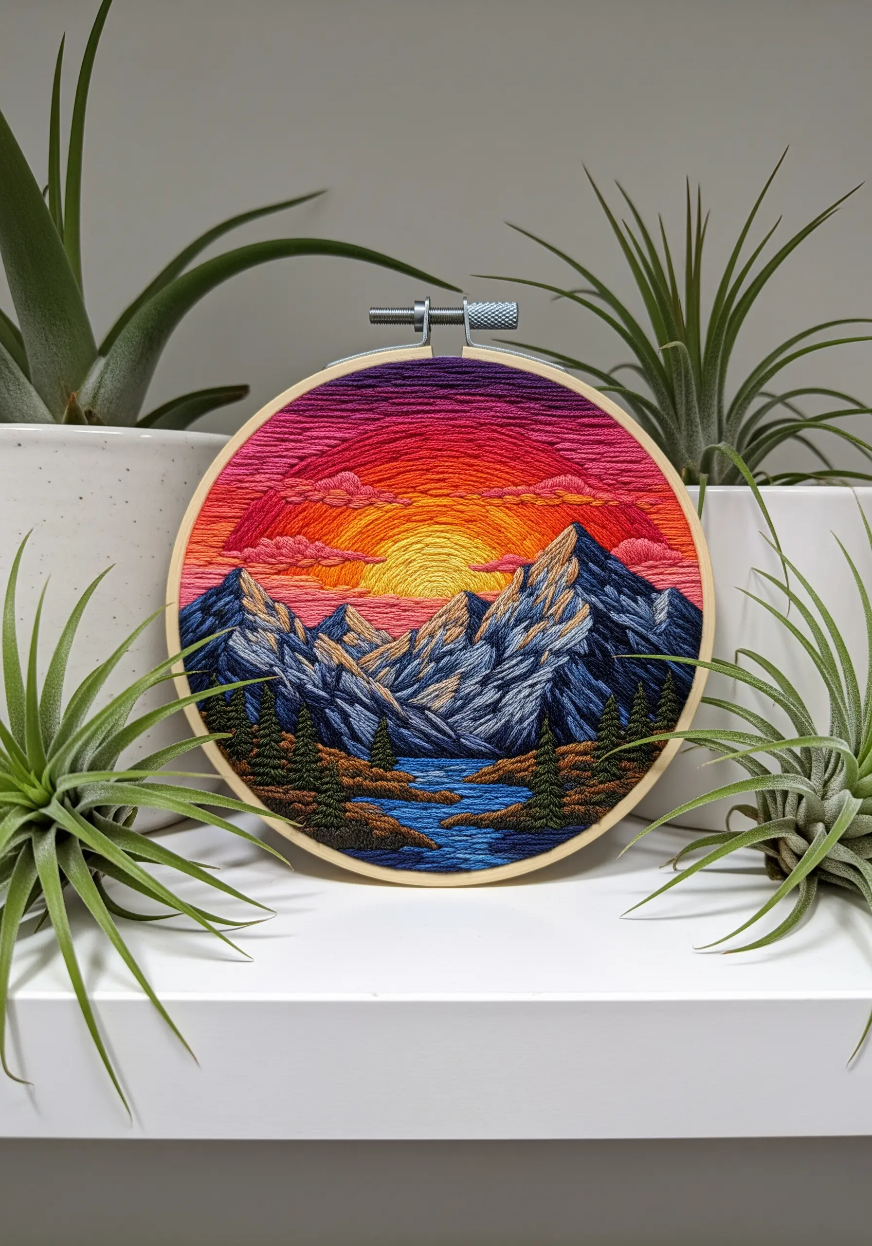 Thread-painted mountain landscape embroidery with a vibrant sunset.