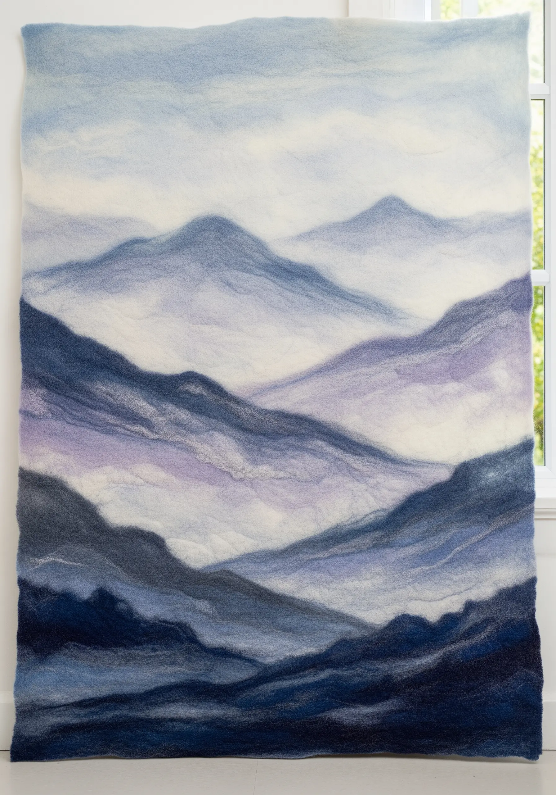 A large needle-felted wall tapestry of misty blue and purple mountain ranges.