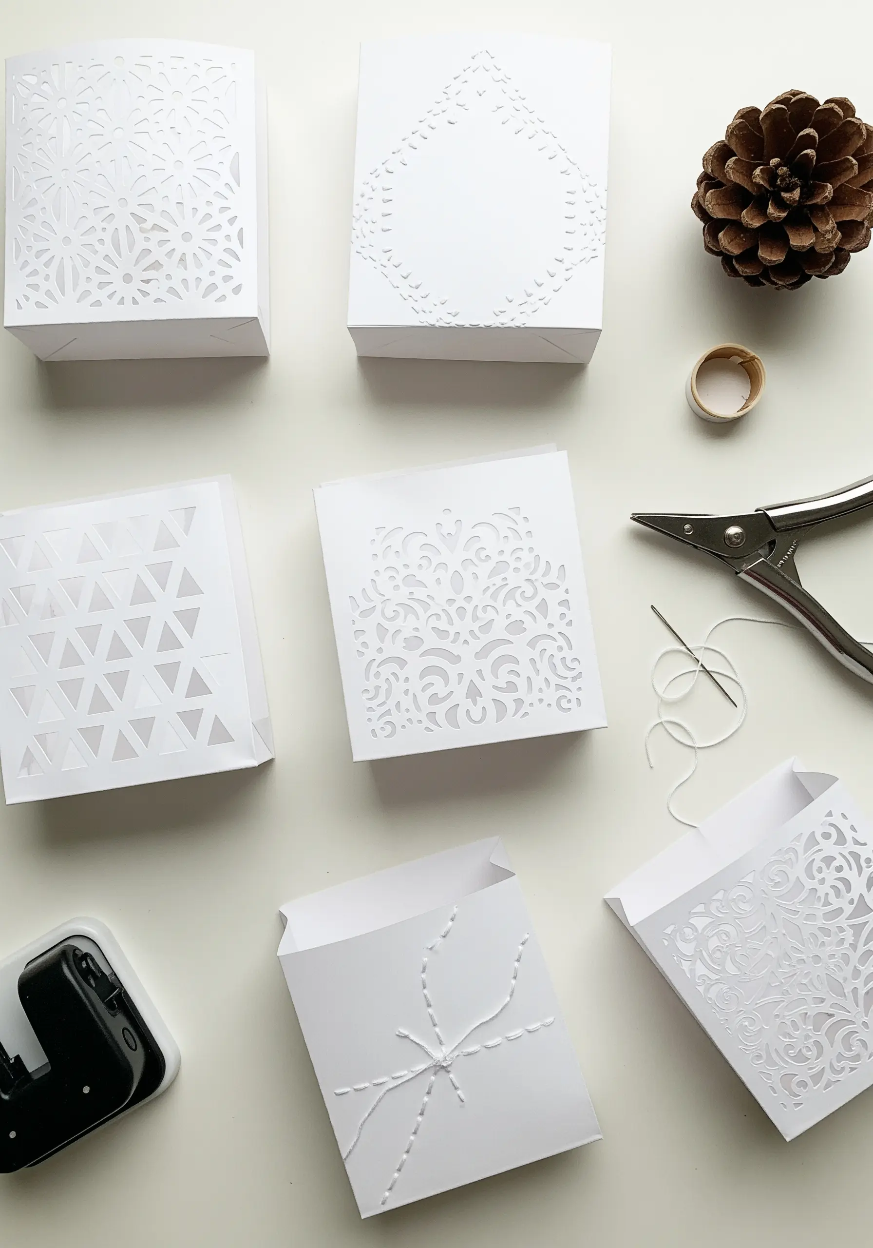 White paper bags with delicate paper-cut designs and simple stitched details.