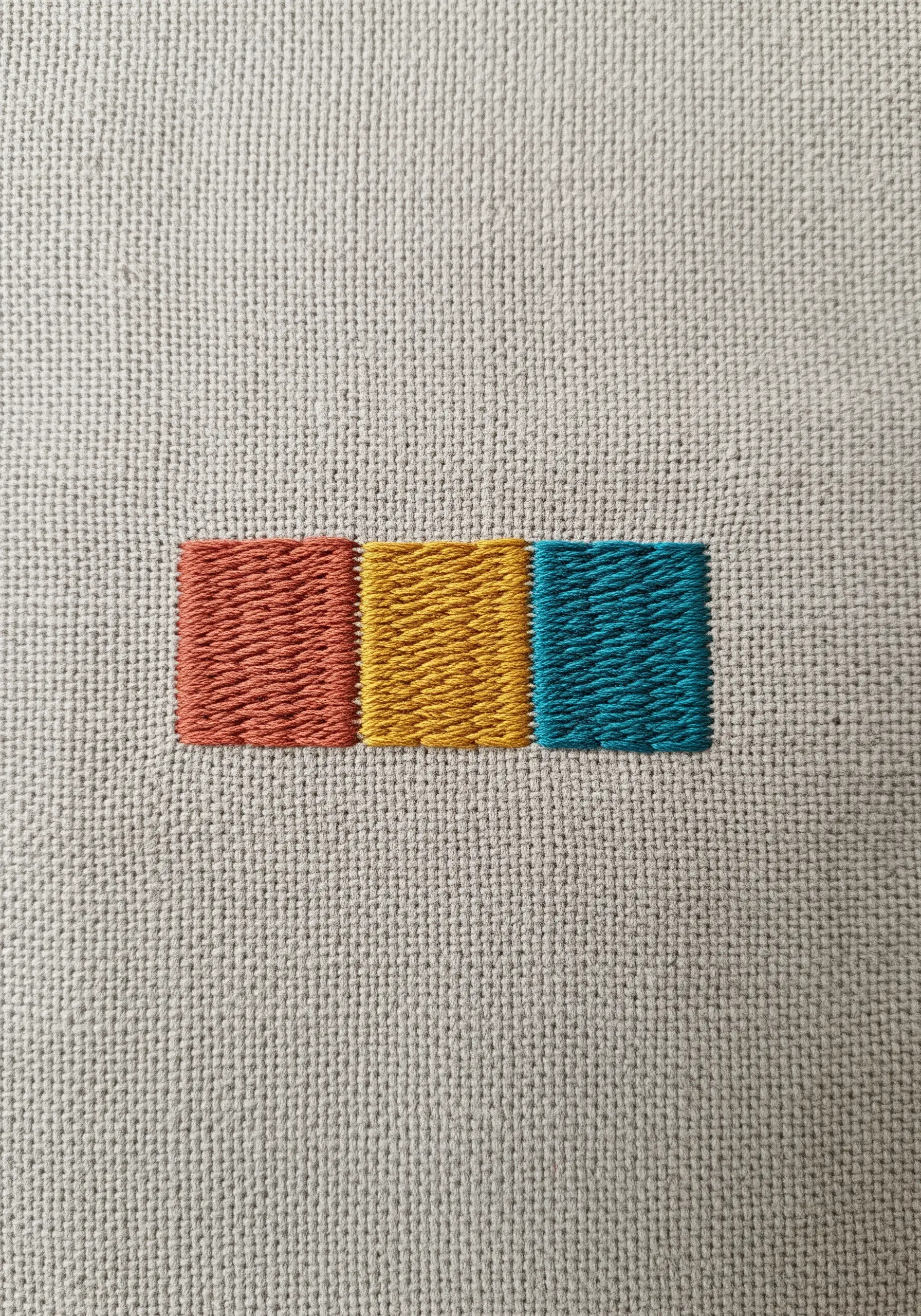 Three small, satin-stitched rectangles in orange, yellow, and teal.