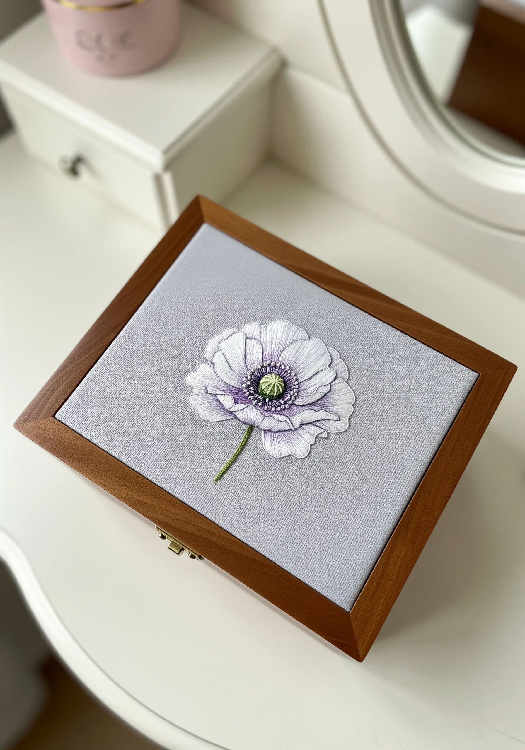 A single white and purple poppy embroidered on fabric inset into a wooden box lid.