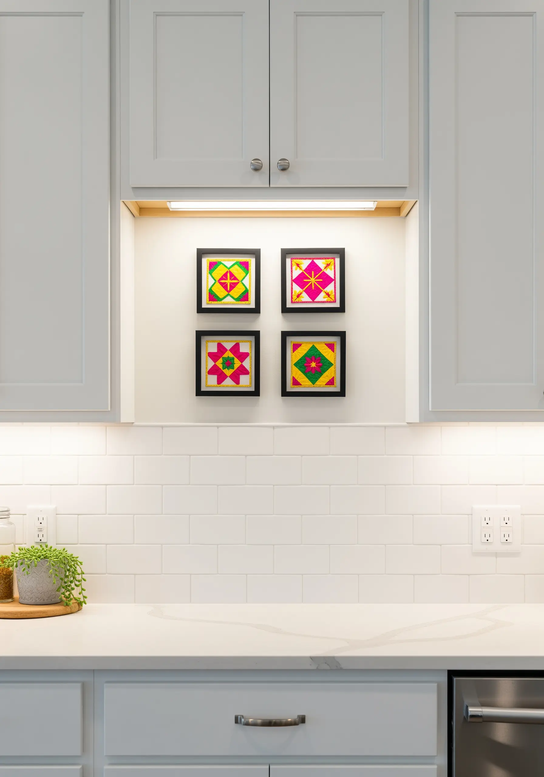 Four small, framed pieces of colorful geometric appliqué art in a modern kitchen.