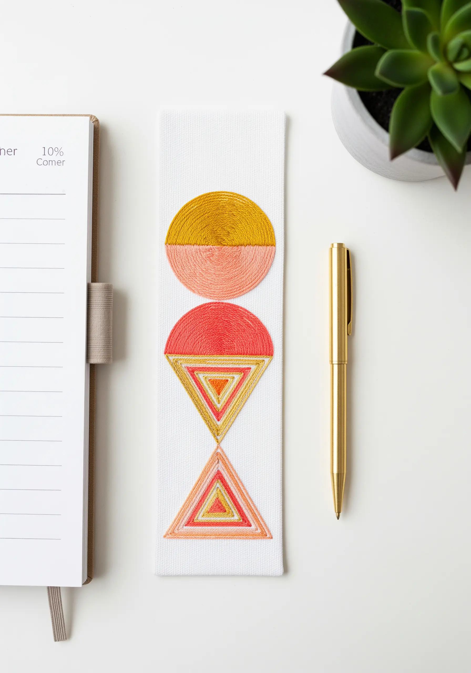 Modern geometric bookmark with satin-stitched circles and triangles in warm tones.