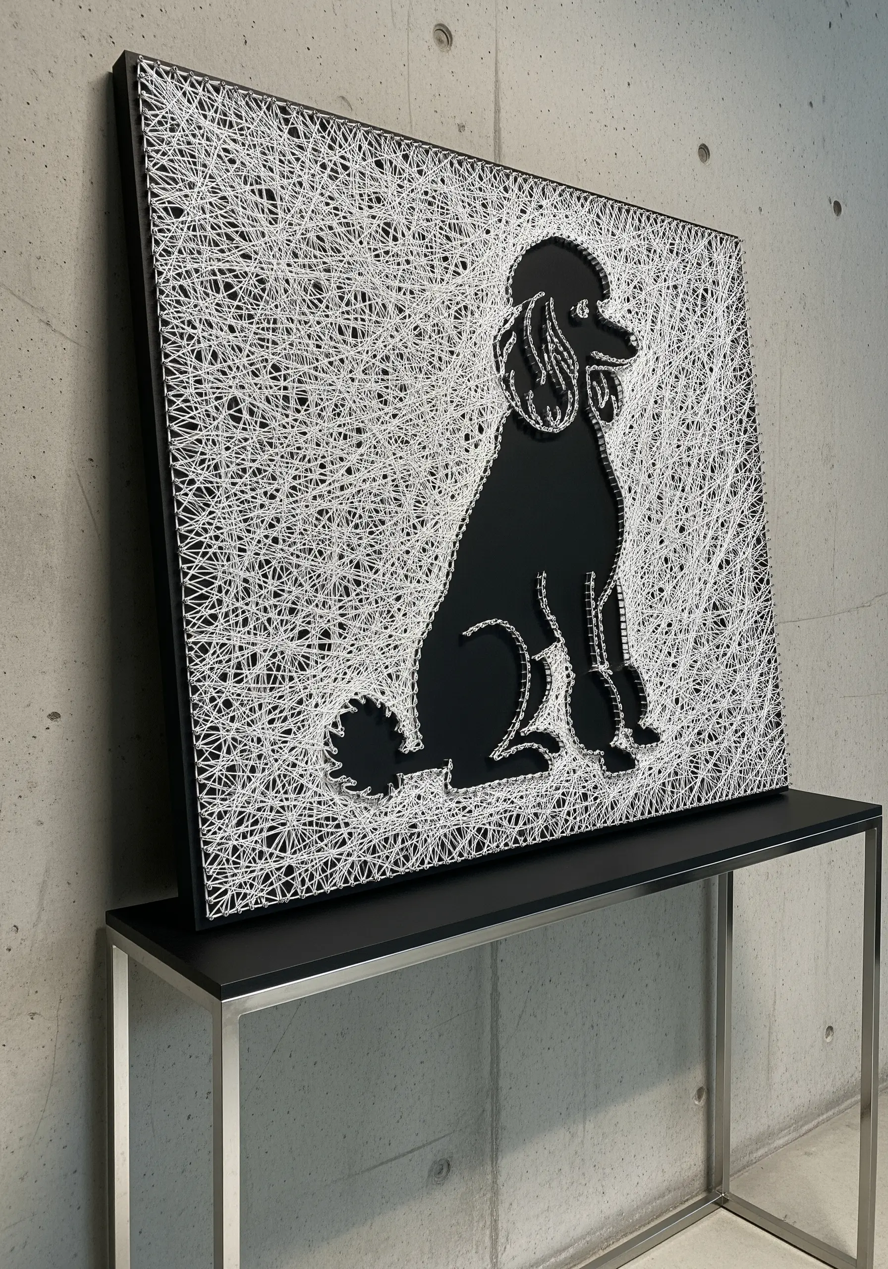 String art of a black poodle silhouette, created by filling the background with white string.