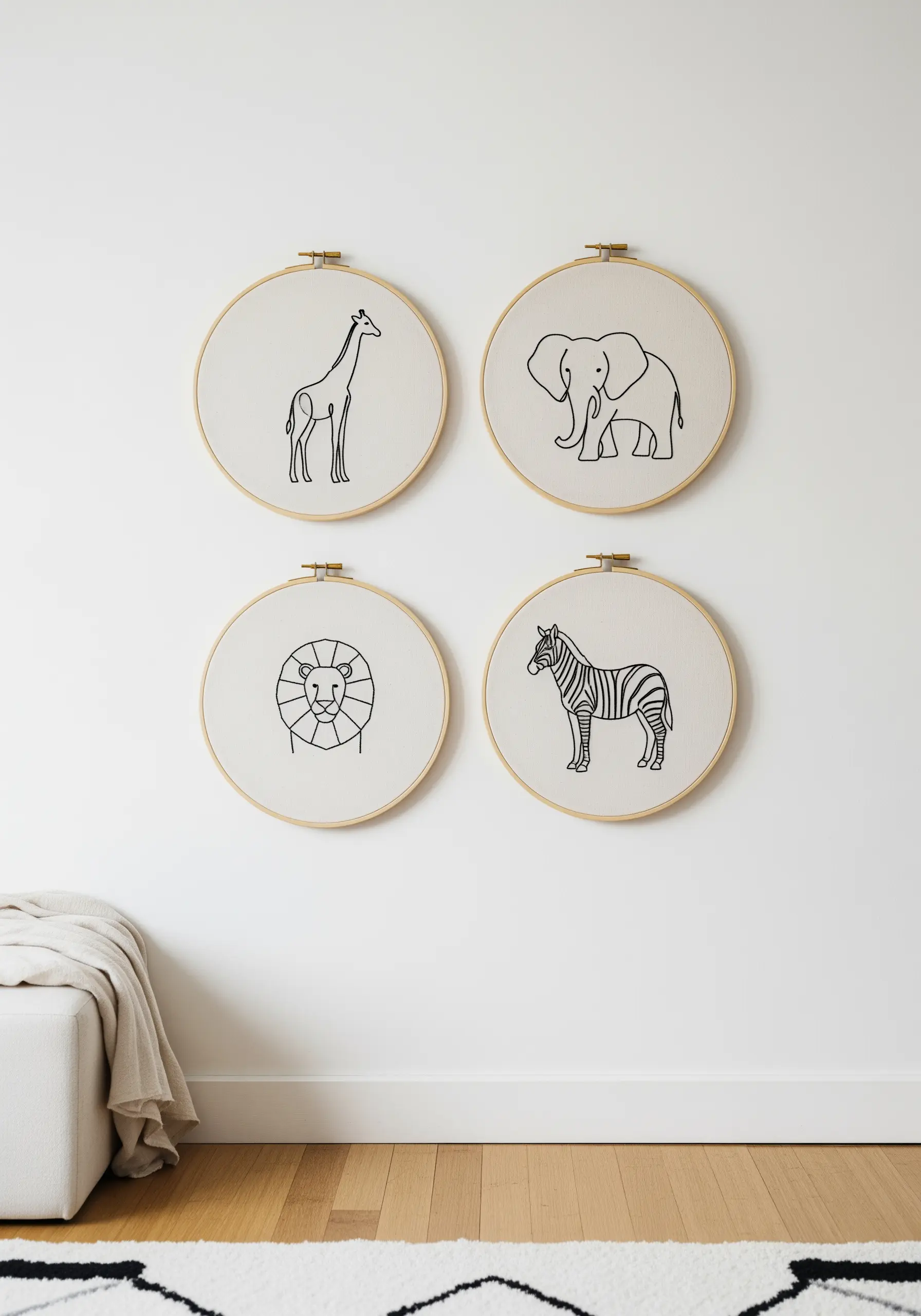 Four embroidery hoops, each with a single minimalist line drawing of a safari animal.