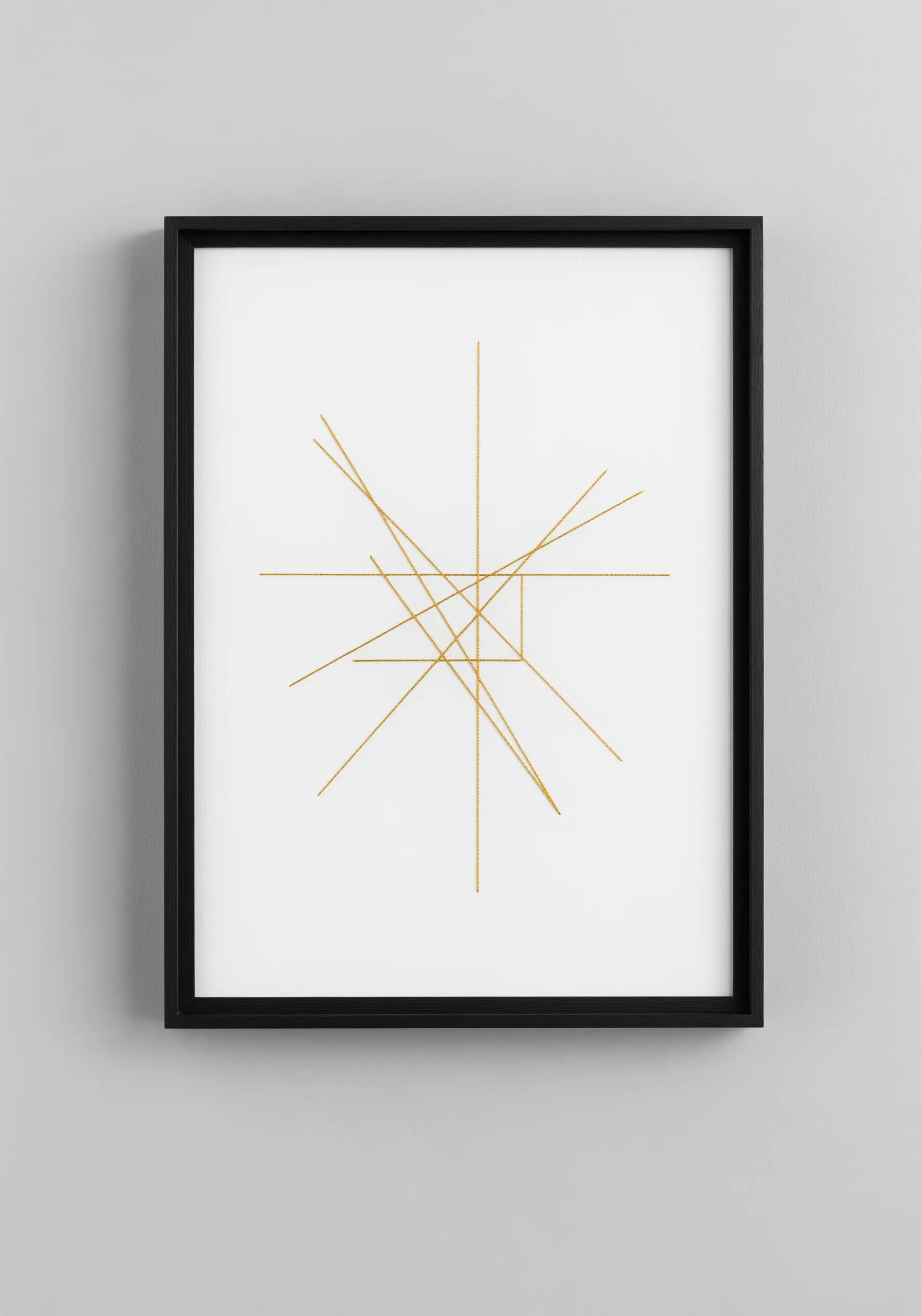 Minimalist gold thread art with intersecting straight lines on white paper in a black frame.
