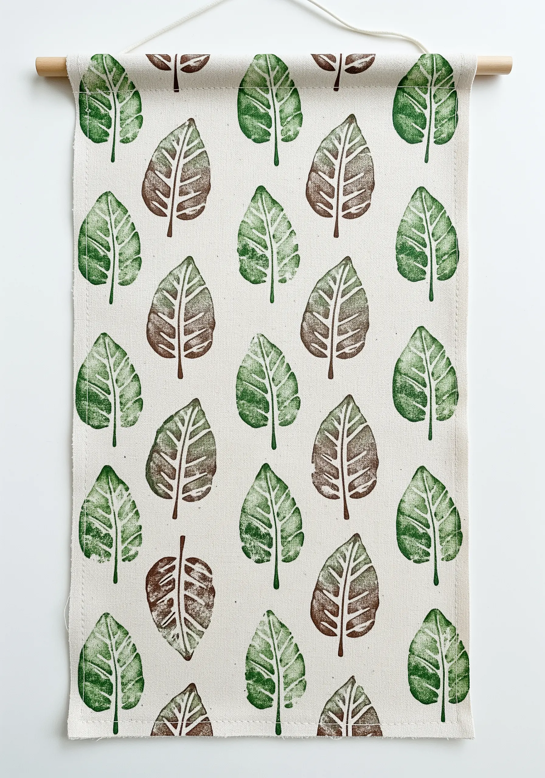 A canvas wall hanging with a pattern of green and brown leaf prints.