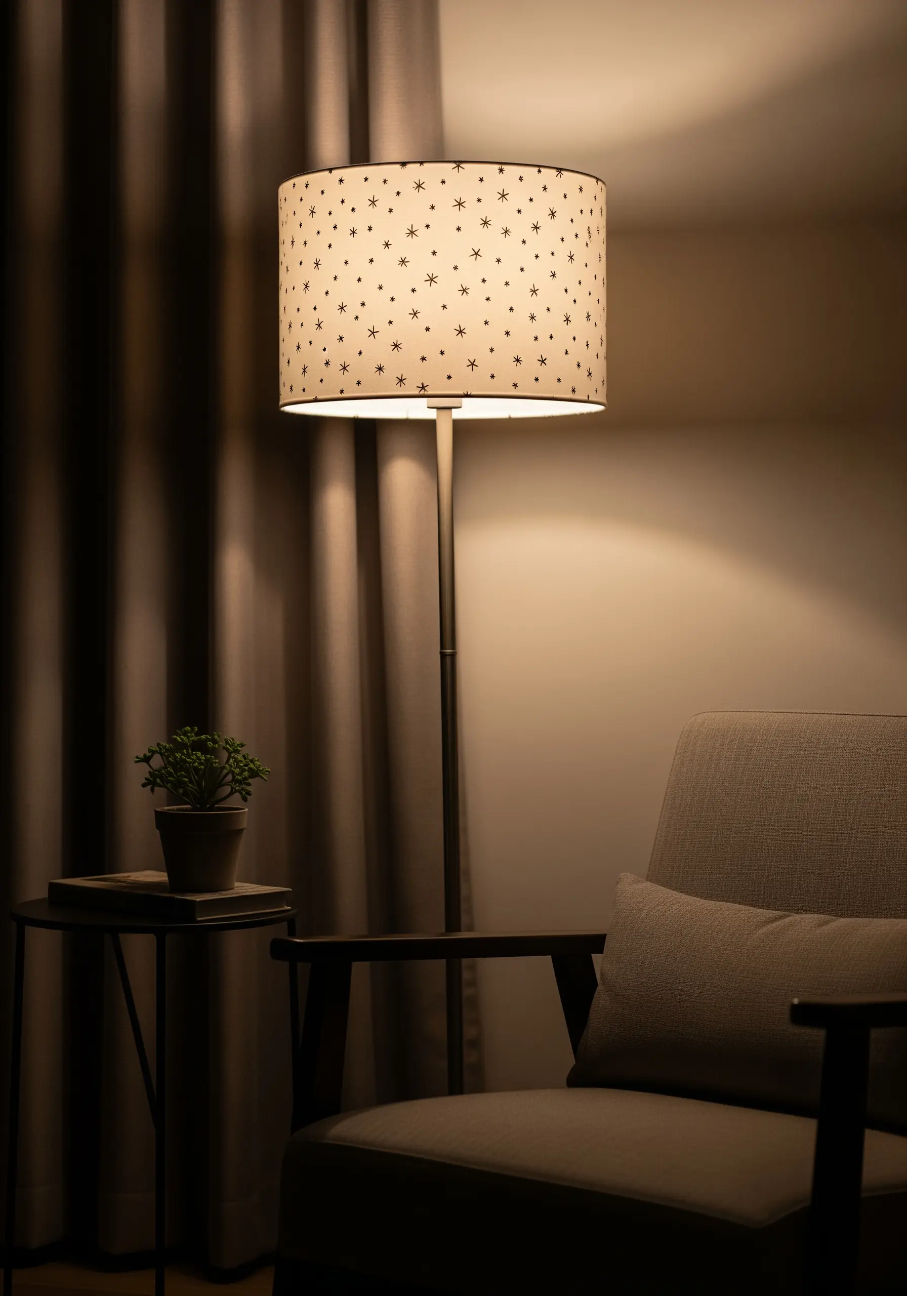 A drum lampshade embroidered with a pattern of small black stars that glows when lit.