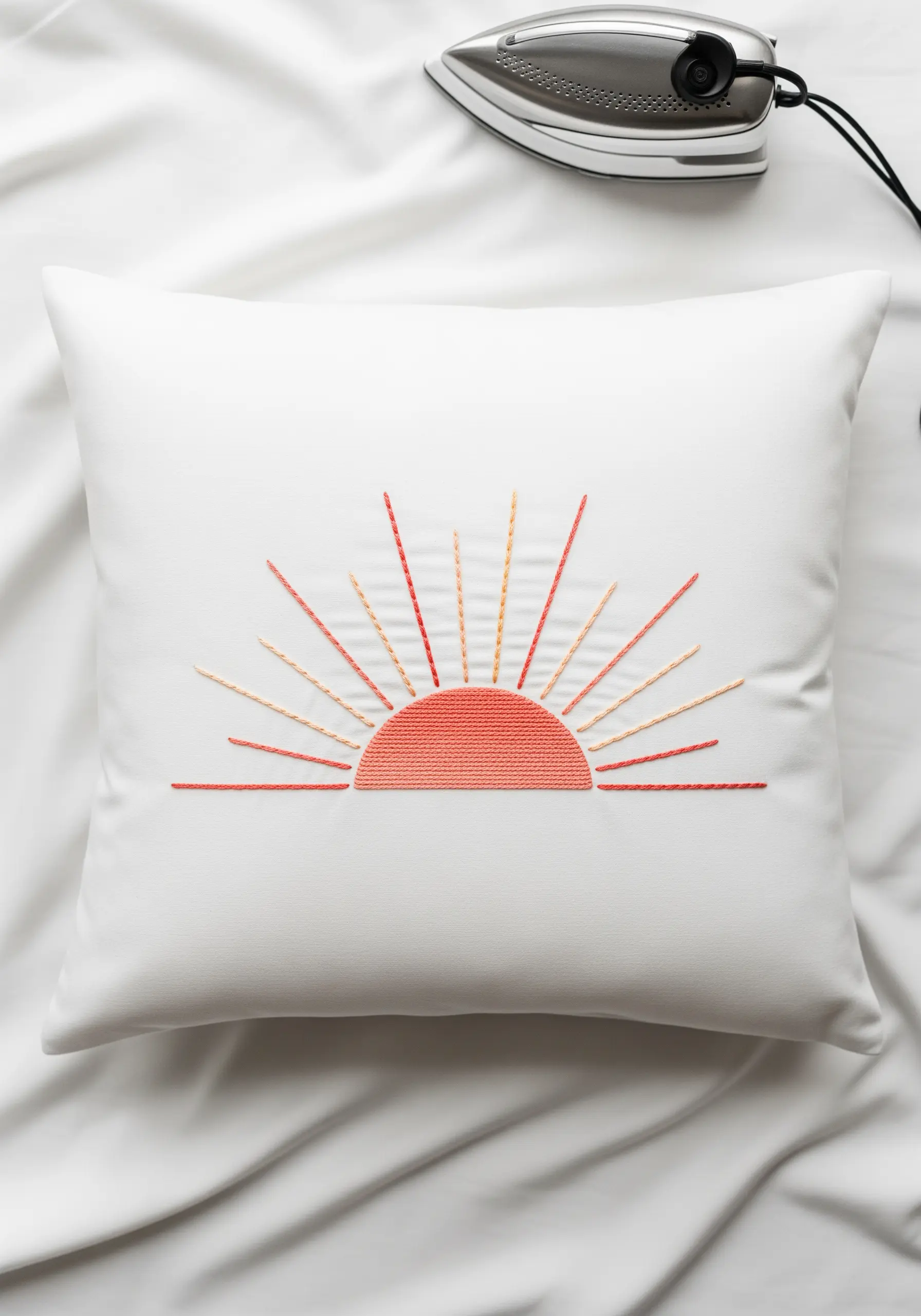 A rising sun embroidered with an orange satin-stitched semi-circle and radiating straight stitches.