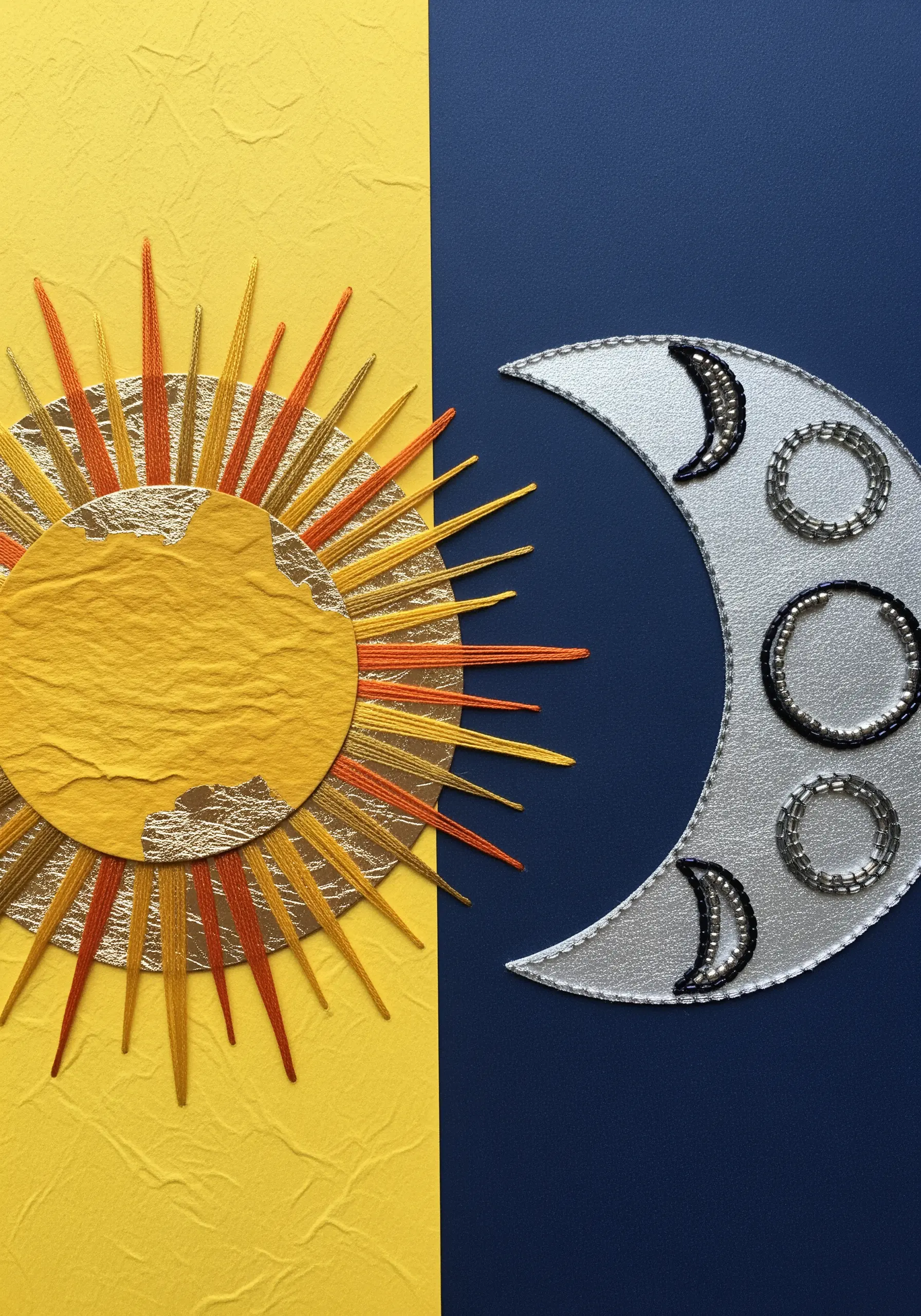 A collage of a sun and moon, with long orange and yellow stitches for sun rays.
