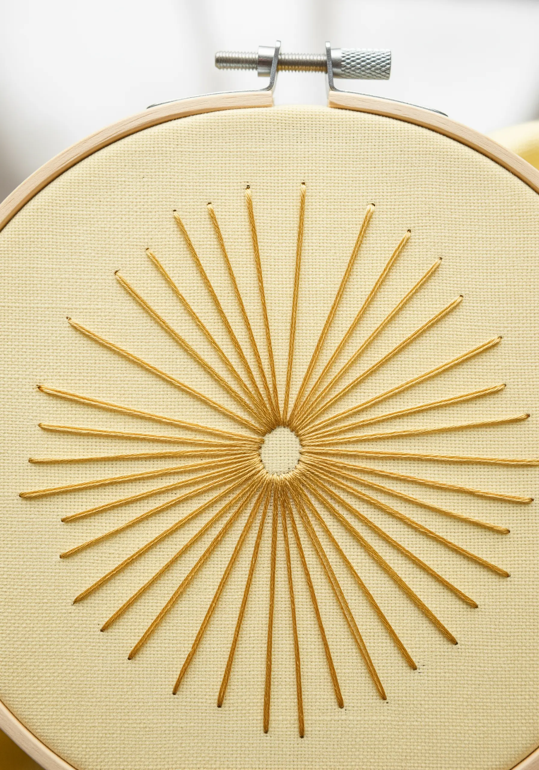 A sunburst of radiating gold stitches with a clean, empty circle at its center.