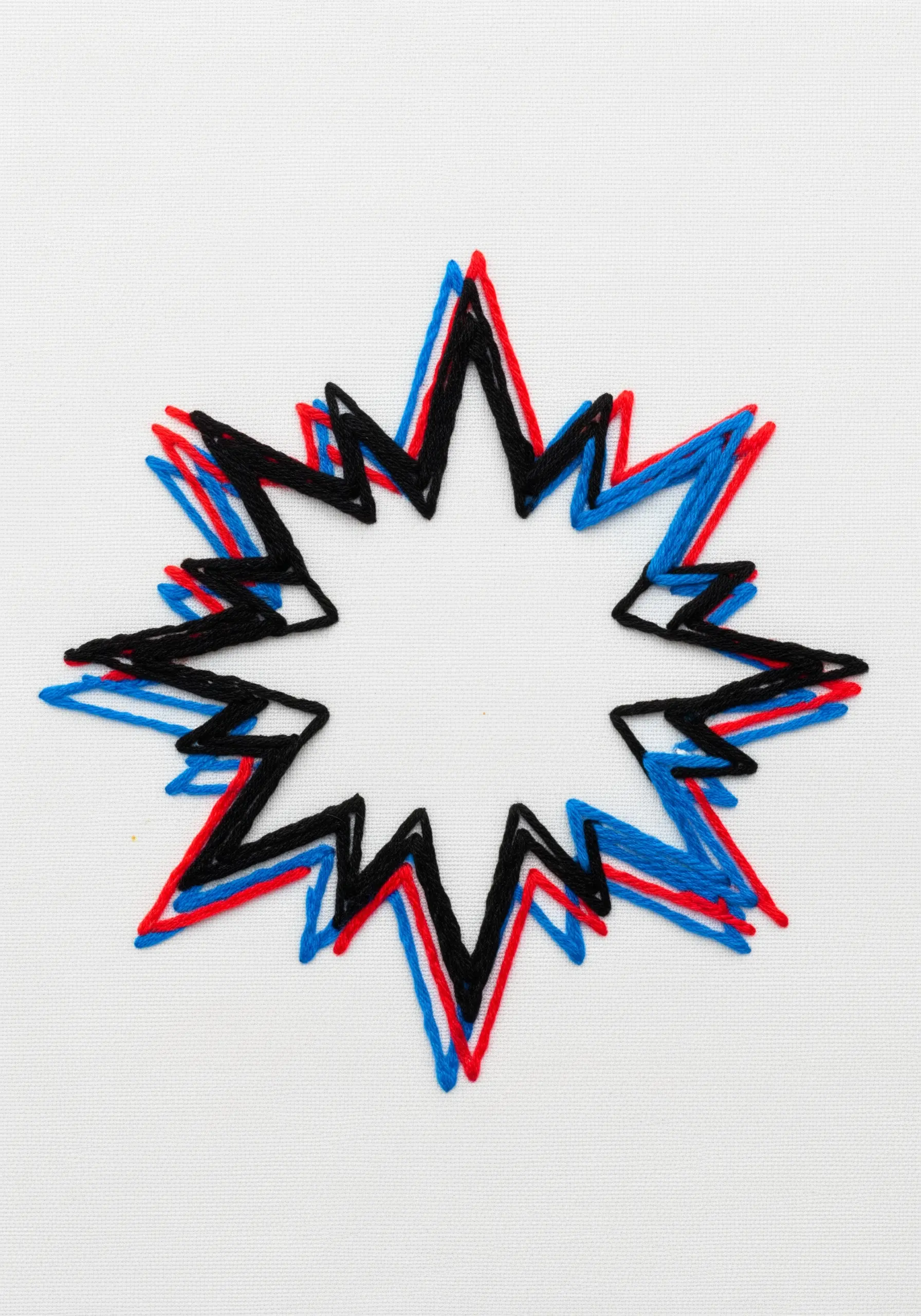 Anaglyph-style embroidery of a starburst with offset outlines in black, red, and blue.