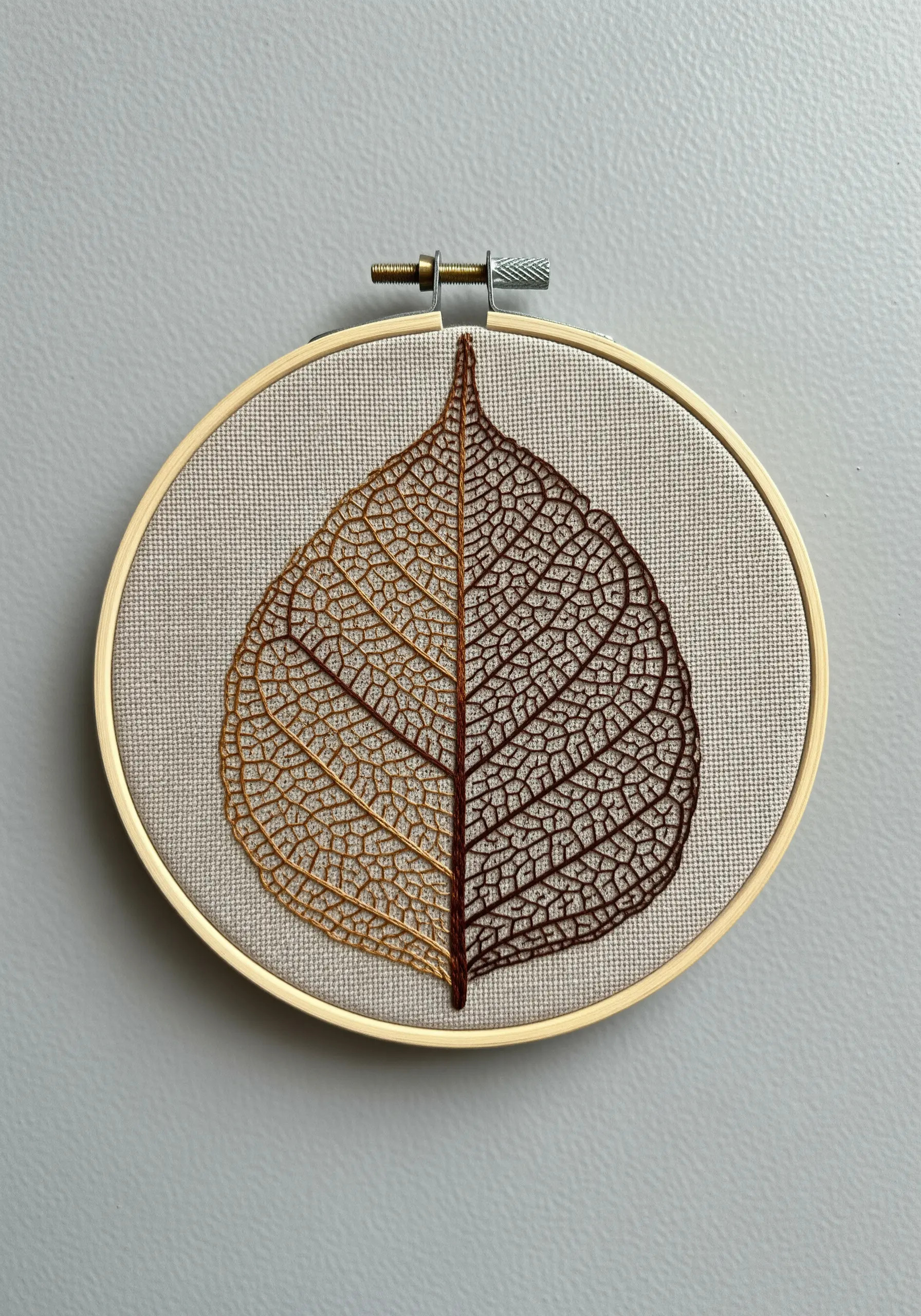 An intricate skeleton leaf embroidered in two tones of brown using single-thread backstitch.