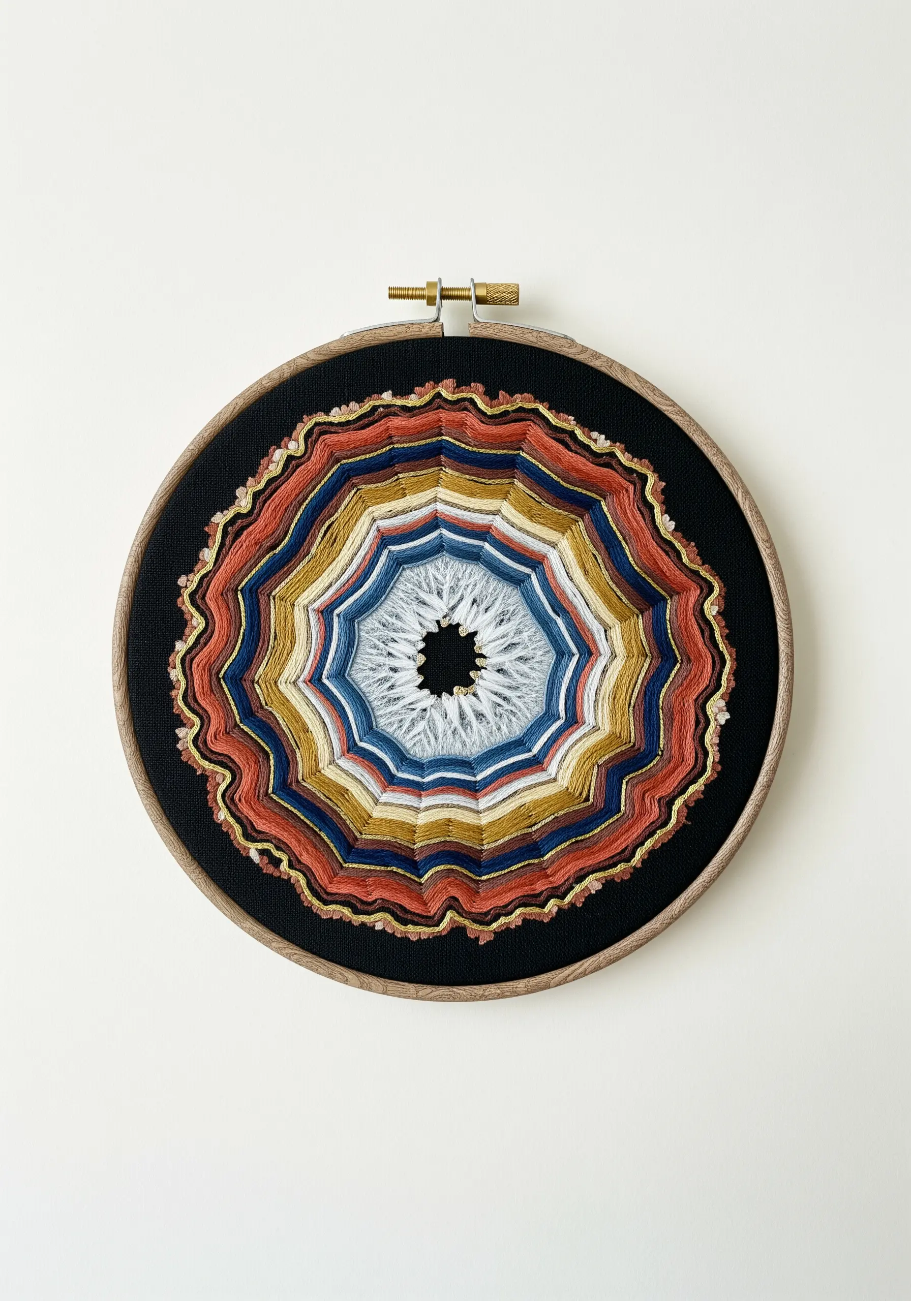Embroidery hoop with concentric, irregular rings of color, resembling a geode slice.