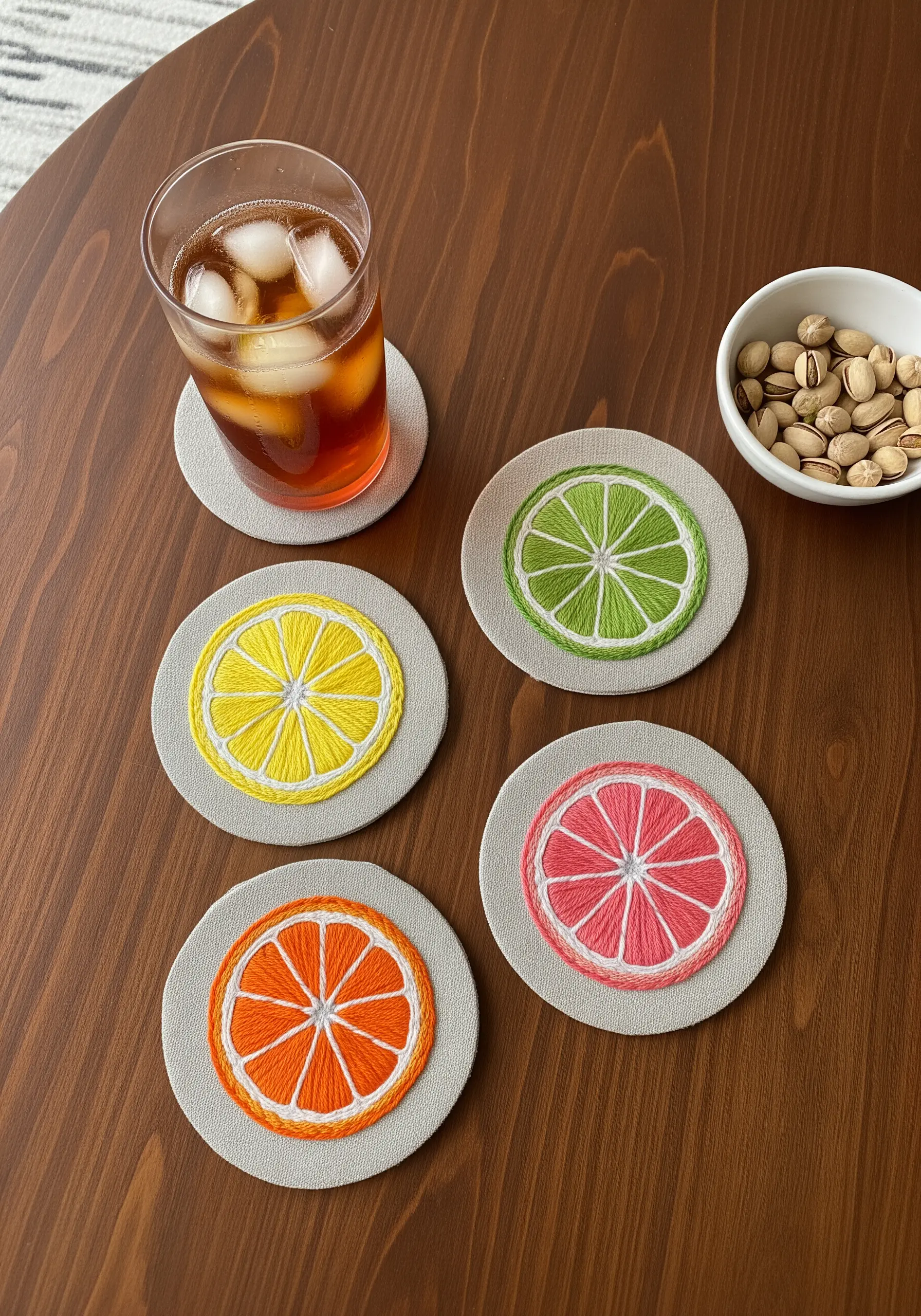 Four embroidered coasters designed as citrus slices: lemon, lime, orange, and grapefruit.