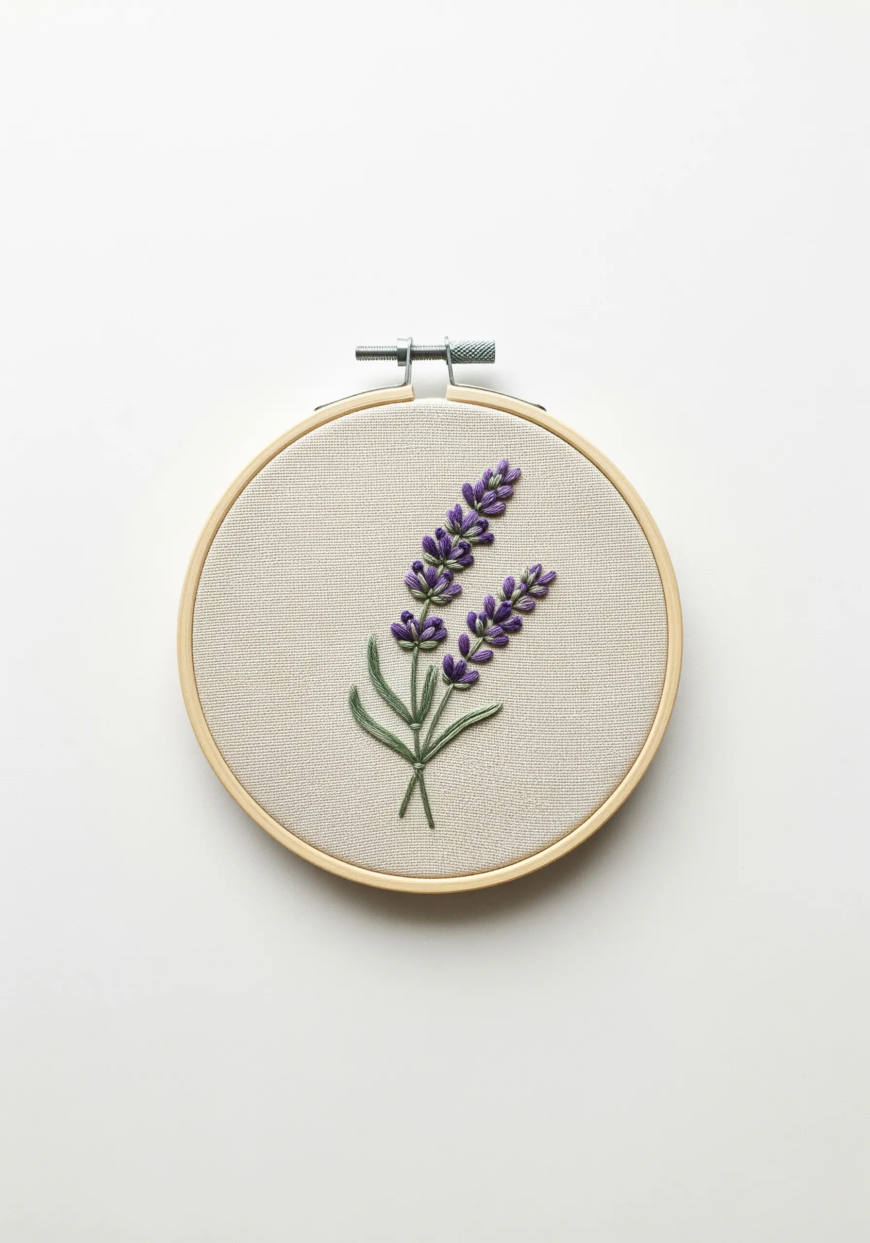 Embroidery of two lavender stems with purple French knots on neutral linen fabric in a hoop.