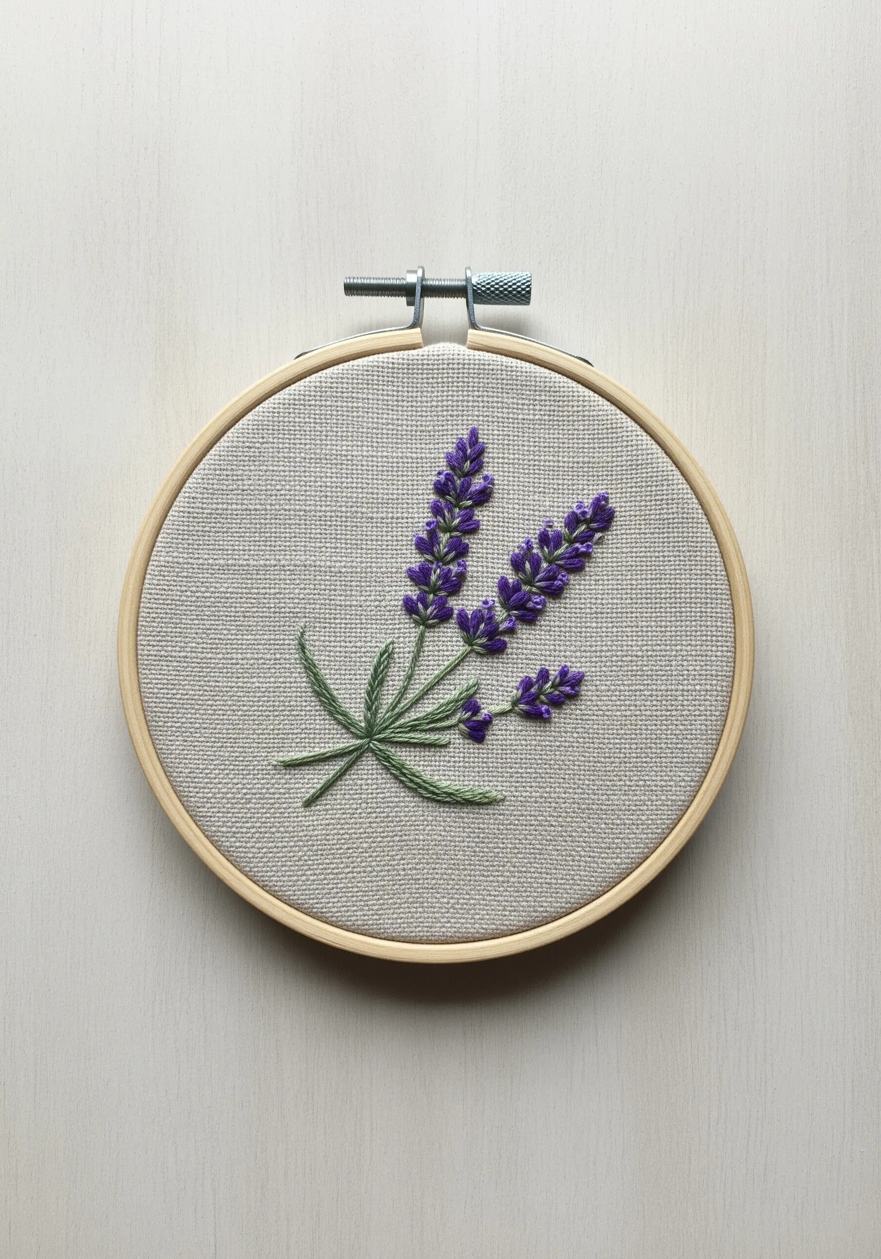 Embroidery of lavender sprigs using French knots and stem stitch on neutral fabric.