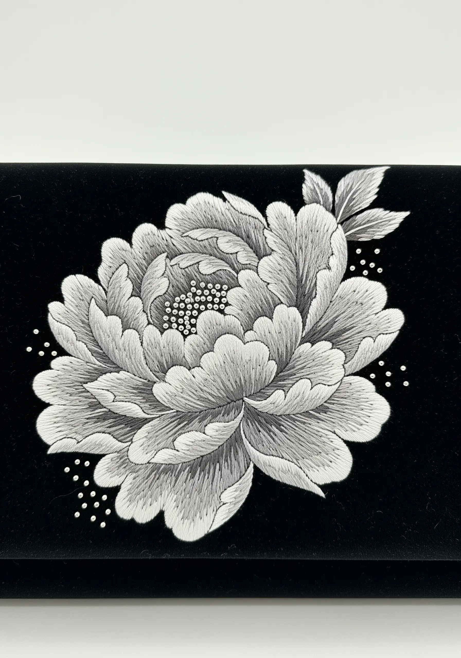 A black-and-white peony on velvet, with French knots for the center.