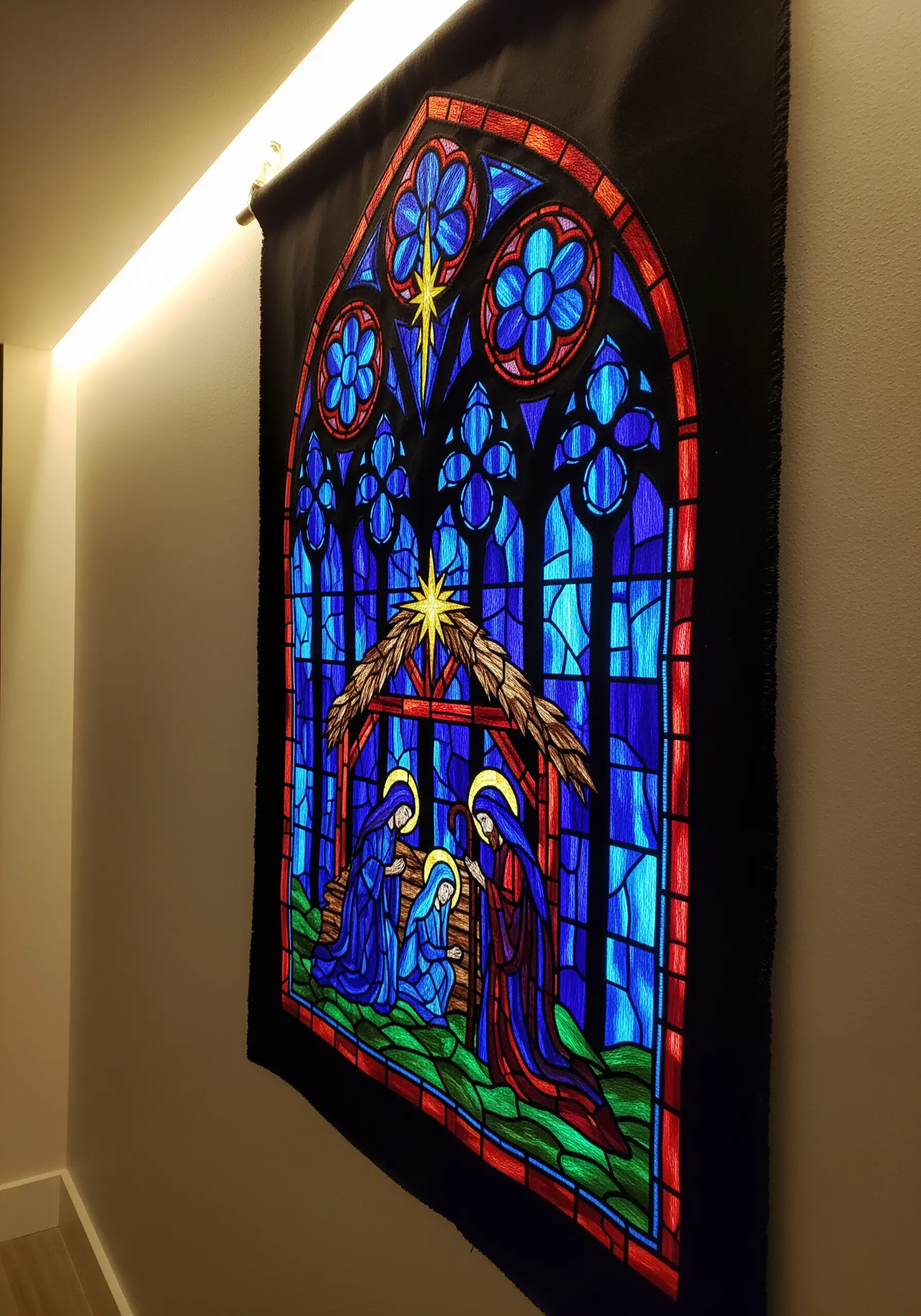 A large wall hanging depicting a nativity scene, embroidered to look like a stained-glass window.