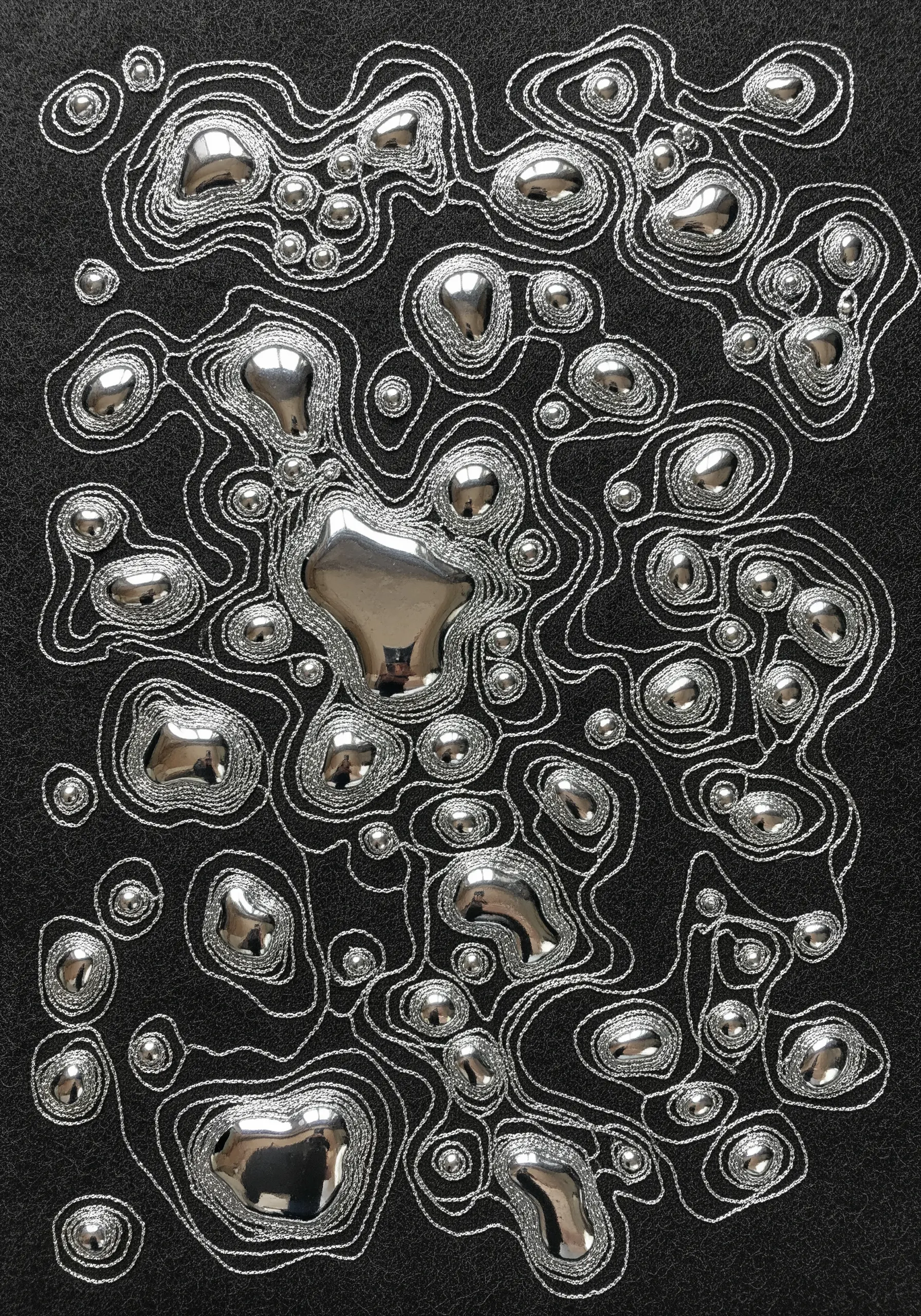Abstract liquid mercury shapes made from raised silver appliqué, outlined with metallic thread.