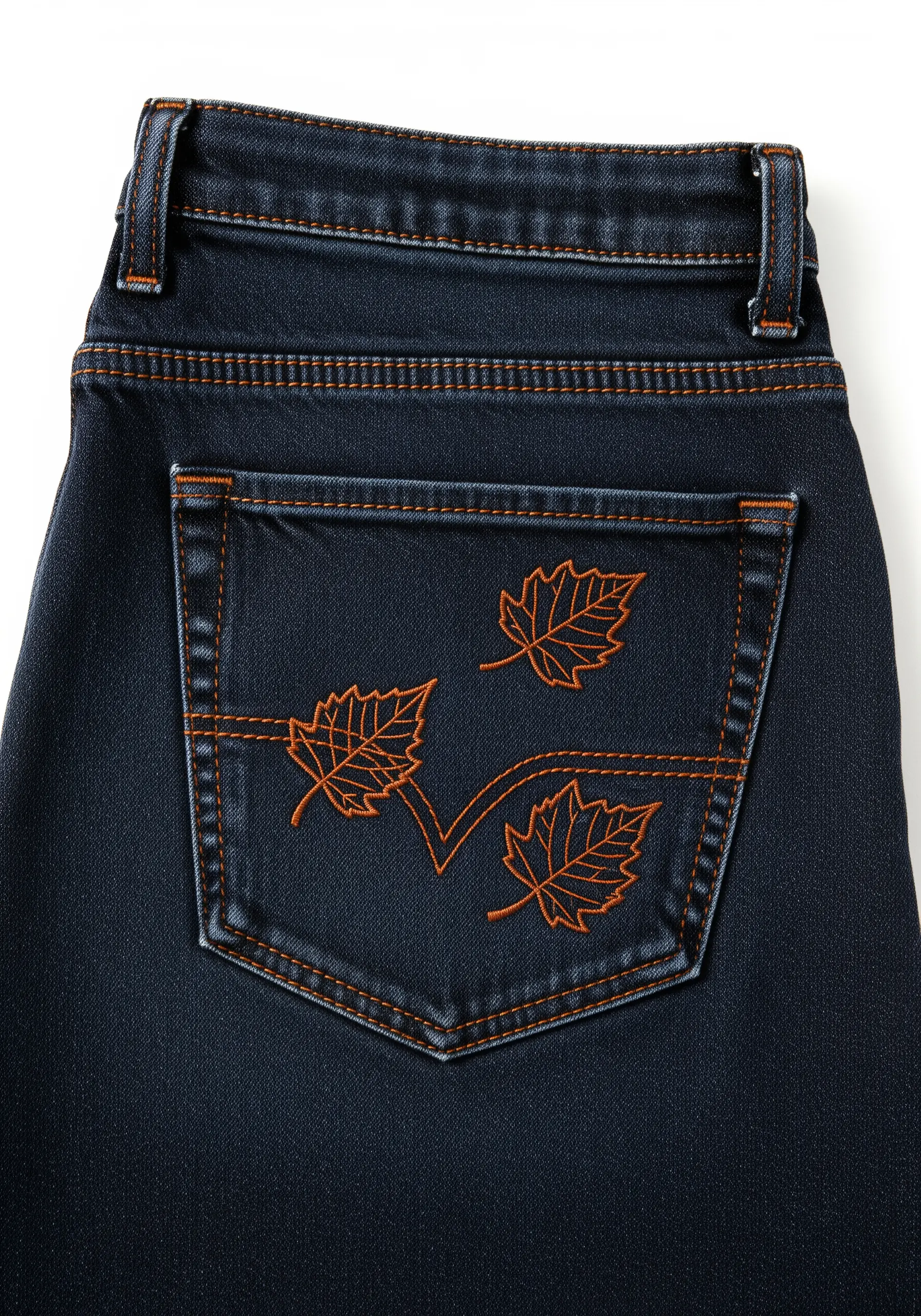 Three scattered maple leaves outlined in orange thread on dark blue jeans.