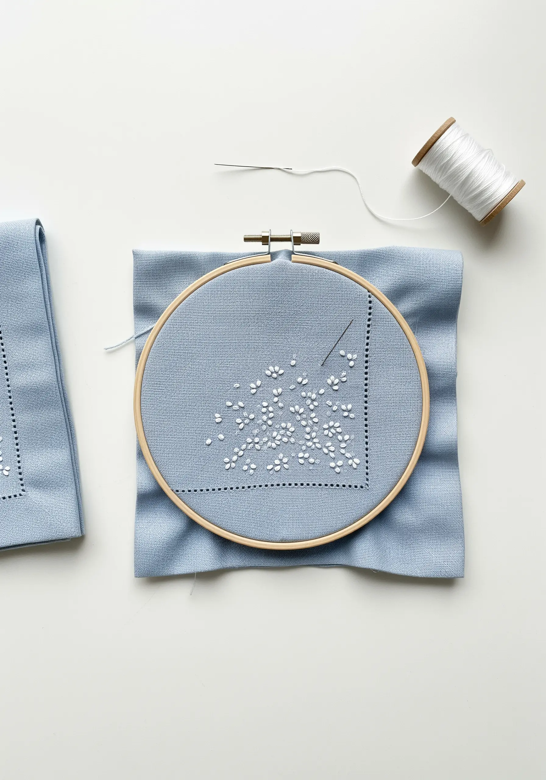 A corner of a blue napkin embroidered with a scattering of tiny white flowers.
