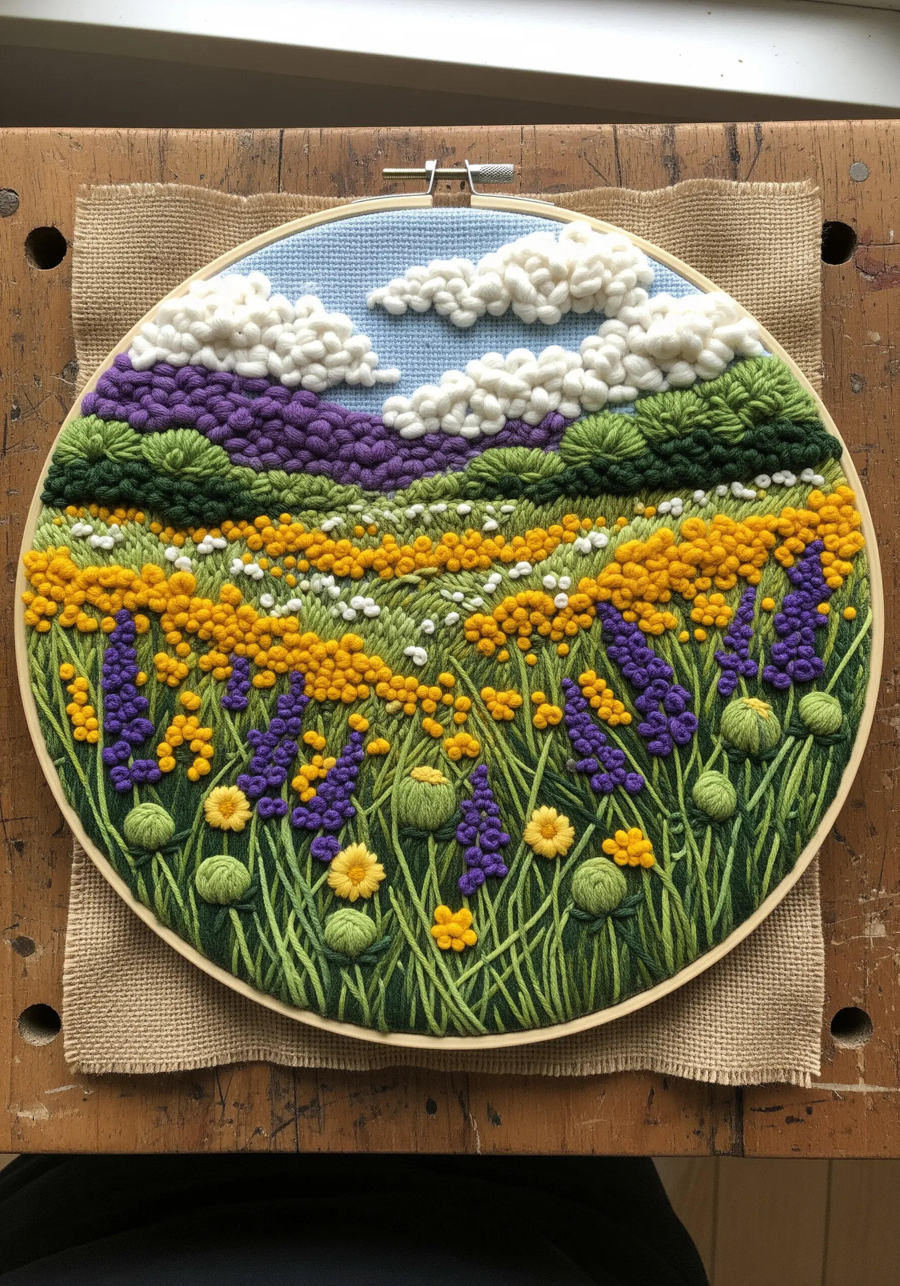 Textured embroidery landscape with French knots for flowers and clouds.