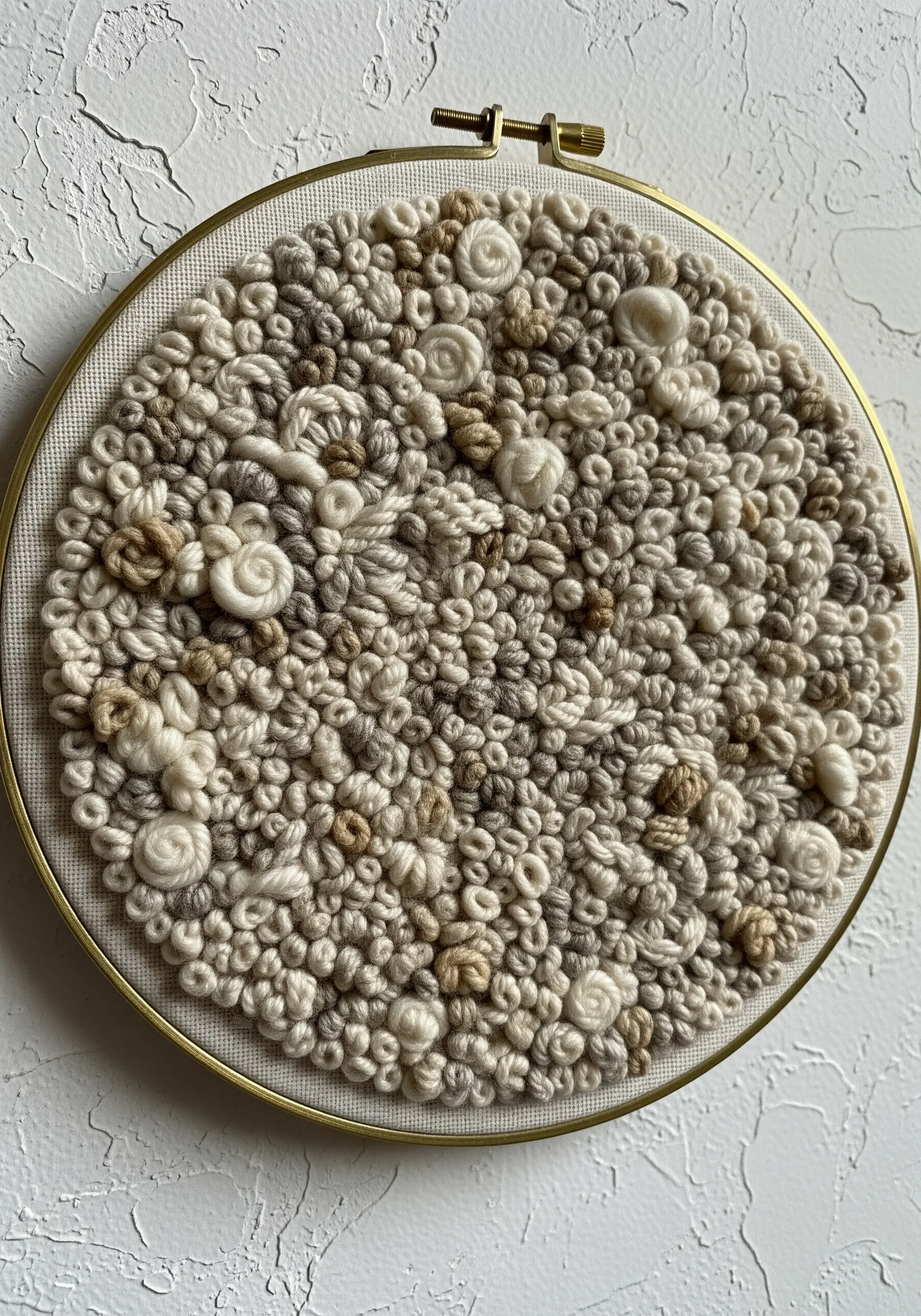 A highly textured embroidery hoop filled with neutral-toned French knots and bullion stitches.