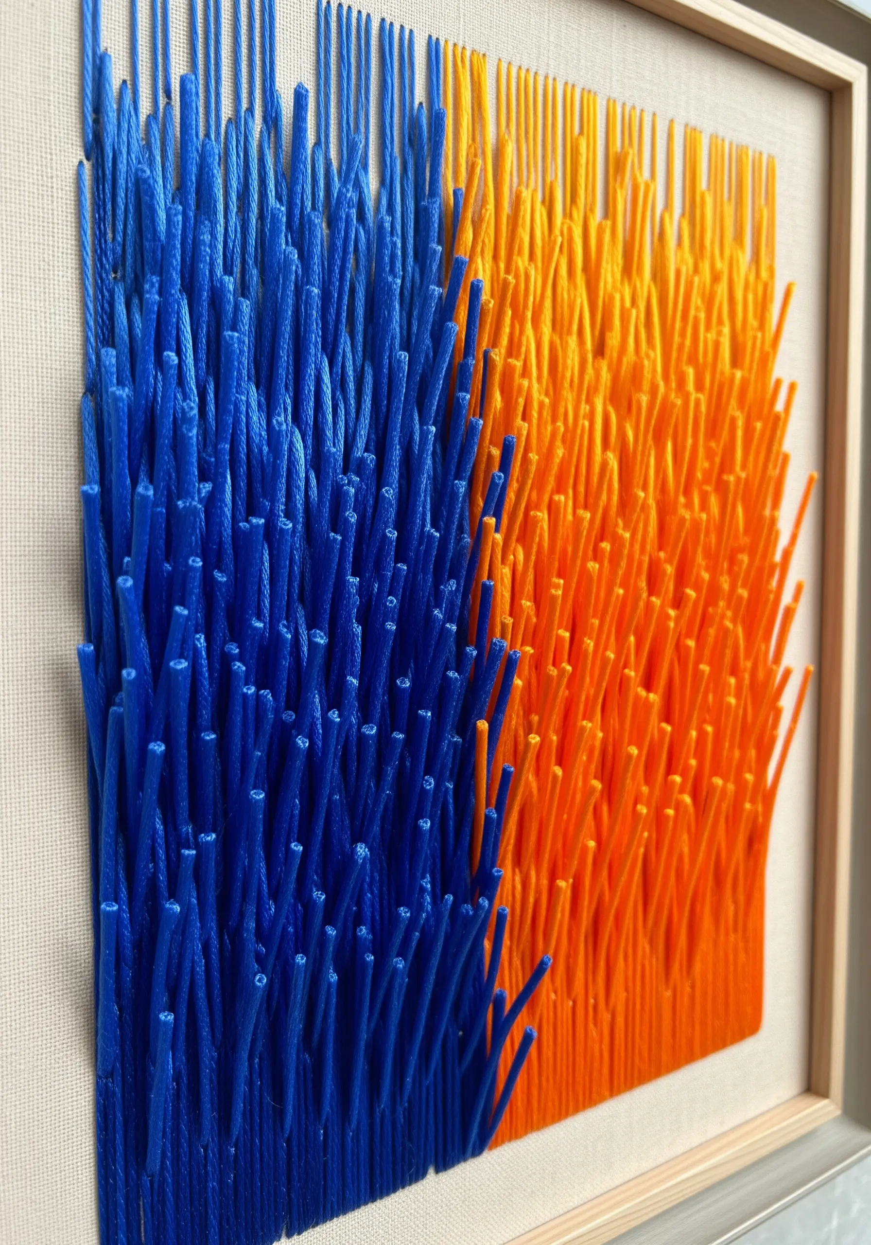 A 3D embroidery with a plush, cut-pile texture in bold blocks of blue and orange.