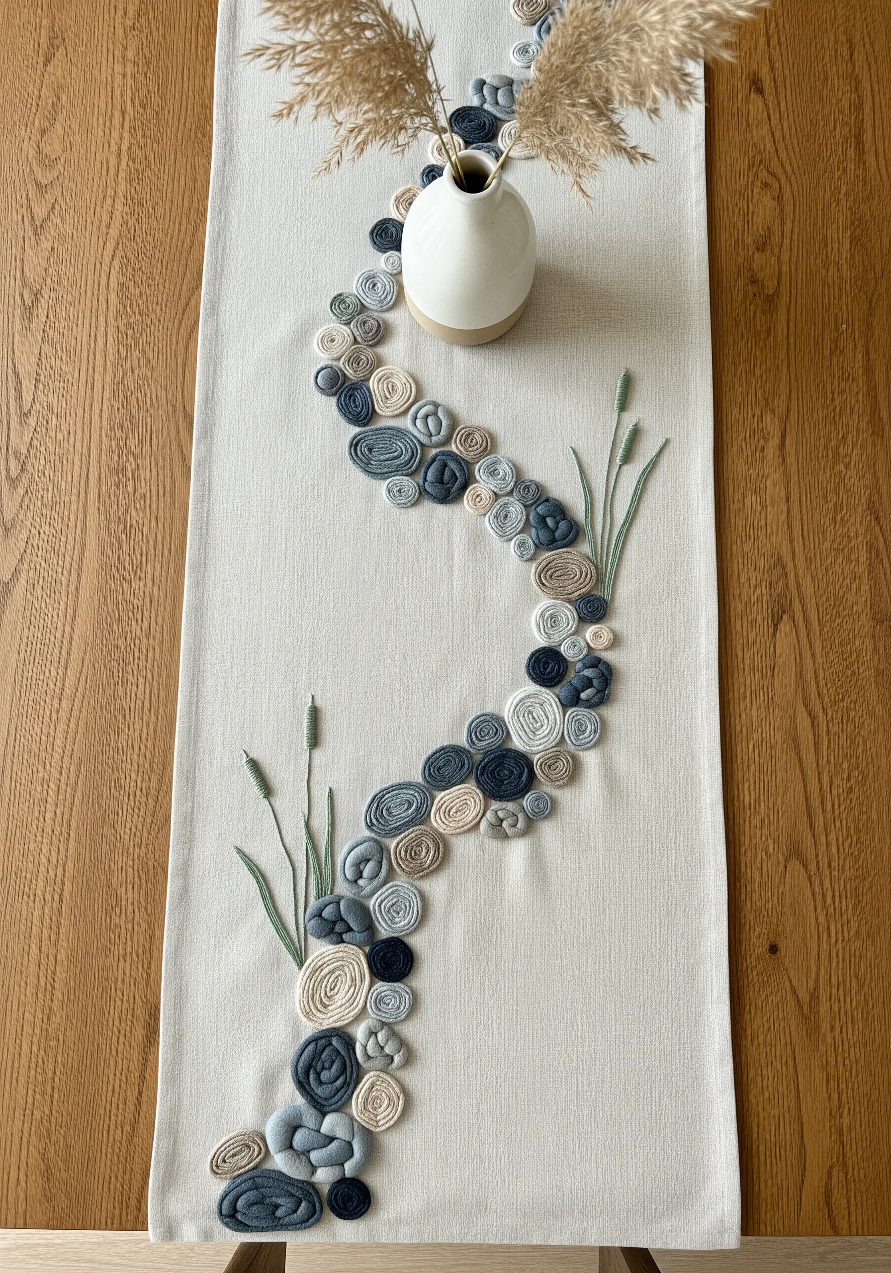 Table runner with a winding path of 3D embroidered fabric 'stones' in muted blues and grays.
