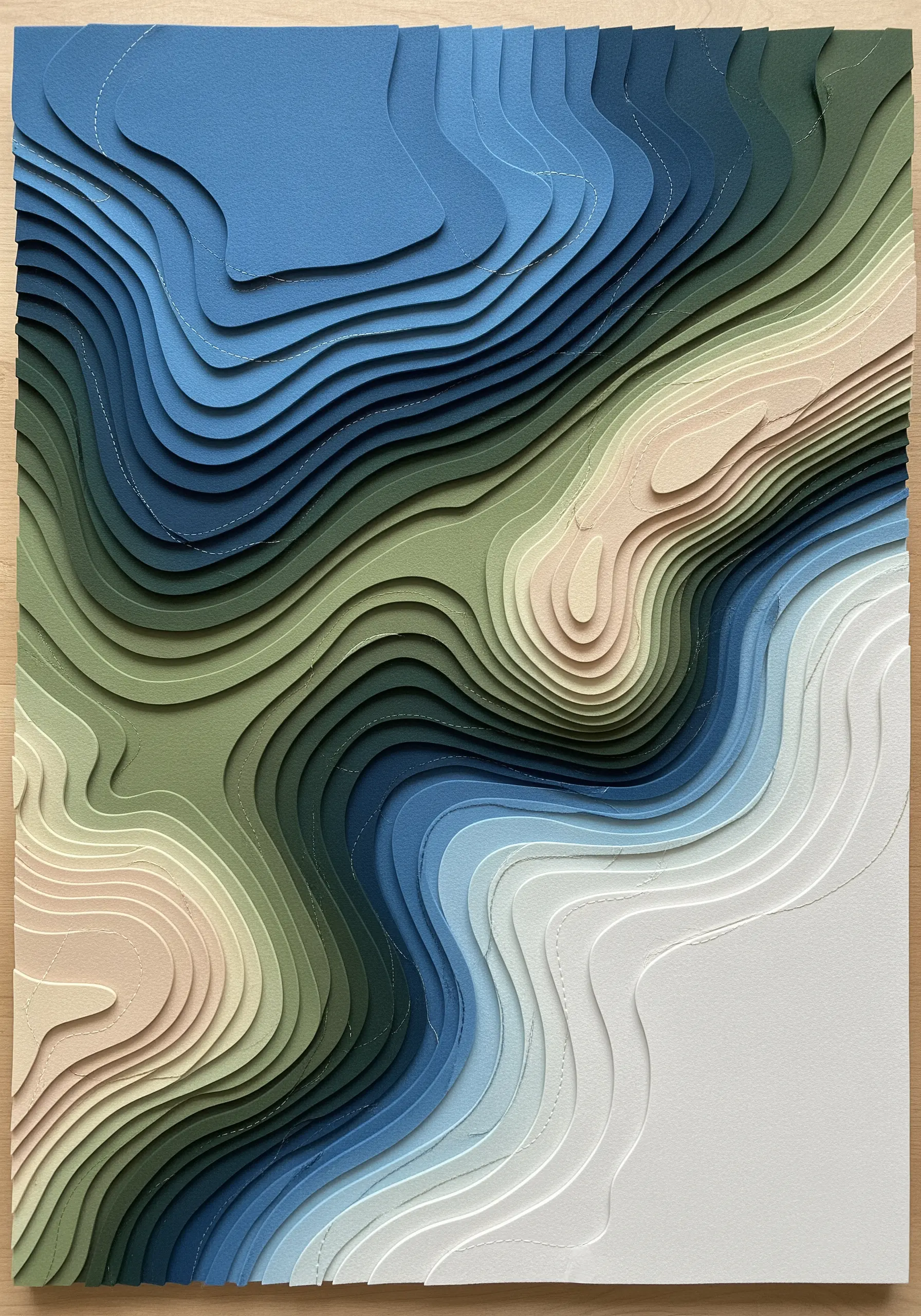 A layered paper art piece showing a topographic map with white stitched details.