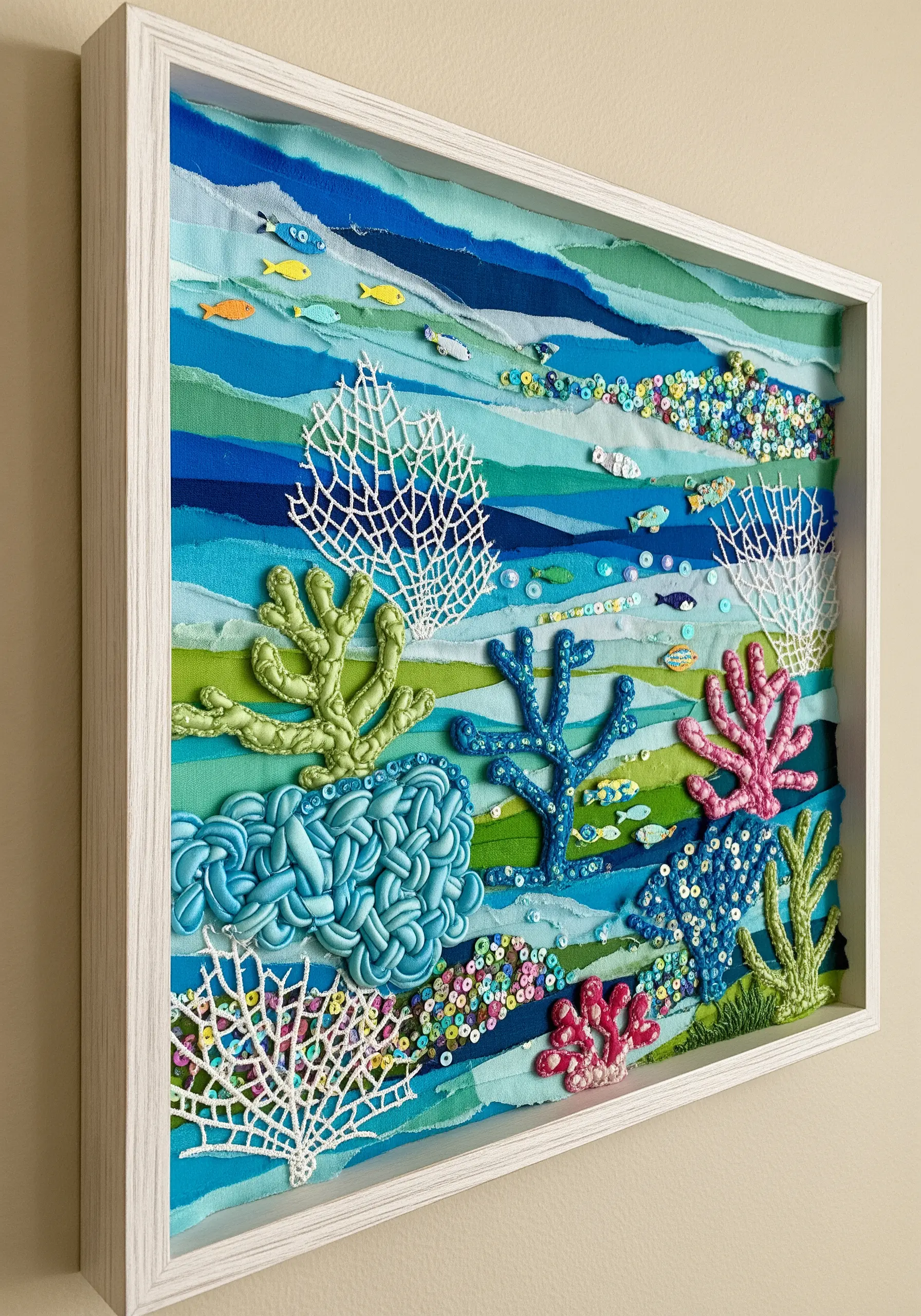 A framed 3D coral reef made with layered fabric, dimensional stitches, lace, and sequins.