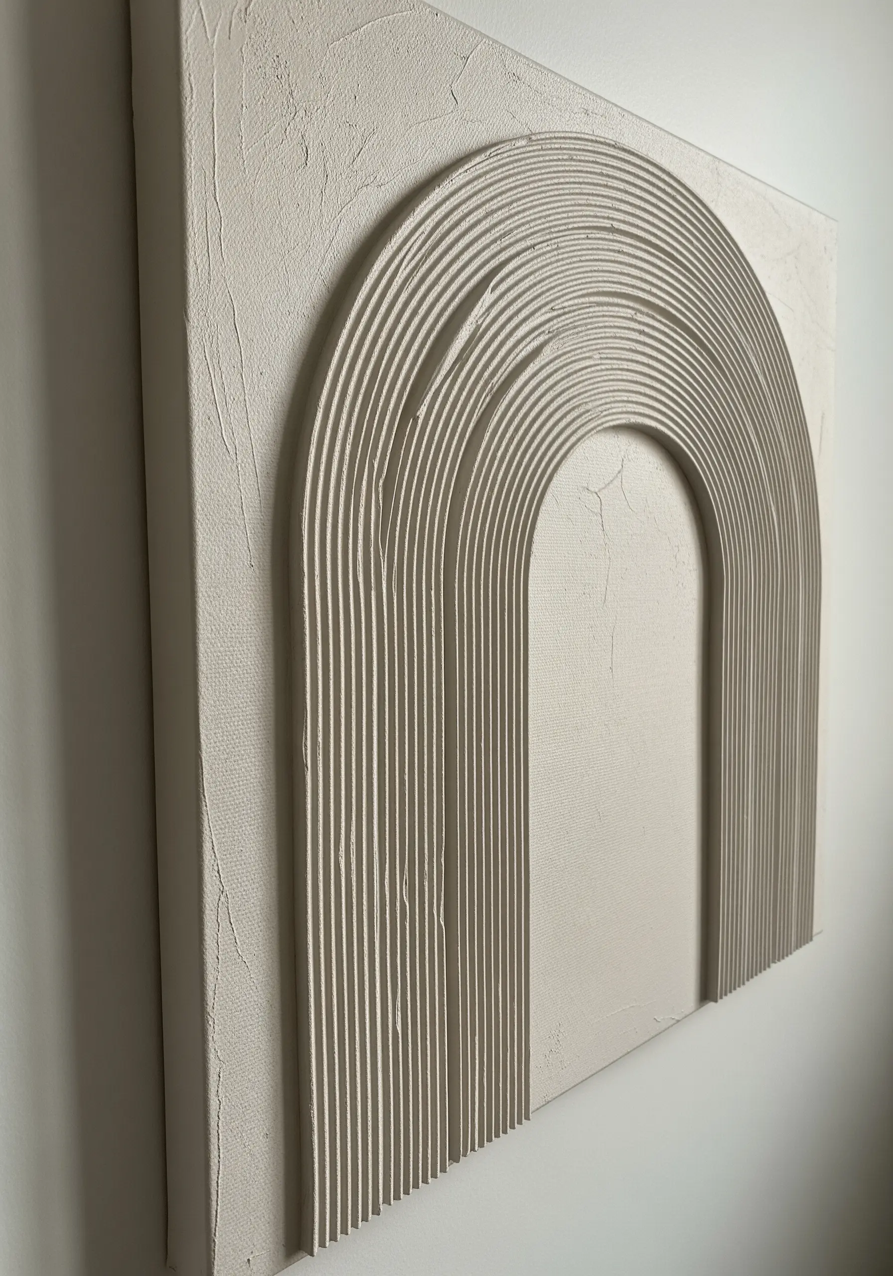 A white canvas with a raised, textured arch pattern created with plaster or joint compound.