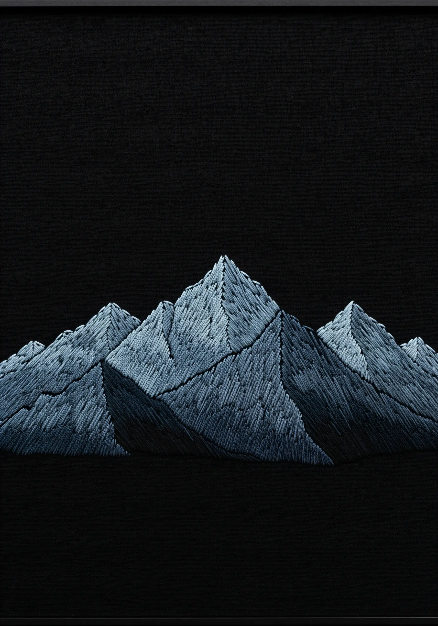 An embroidered mountain range on black fabric, with stitch direction creating sharp facets.