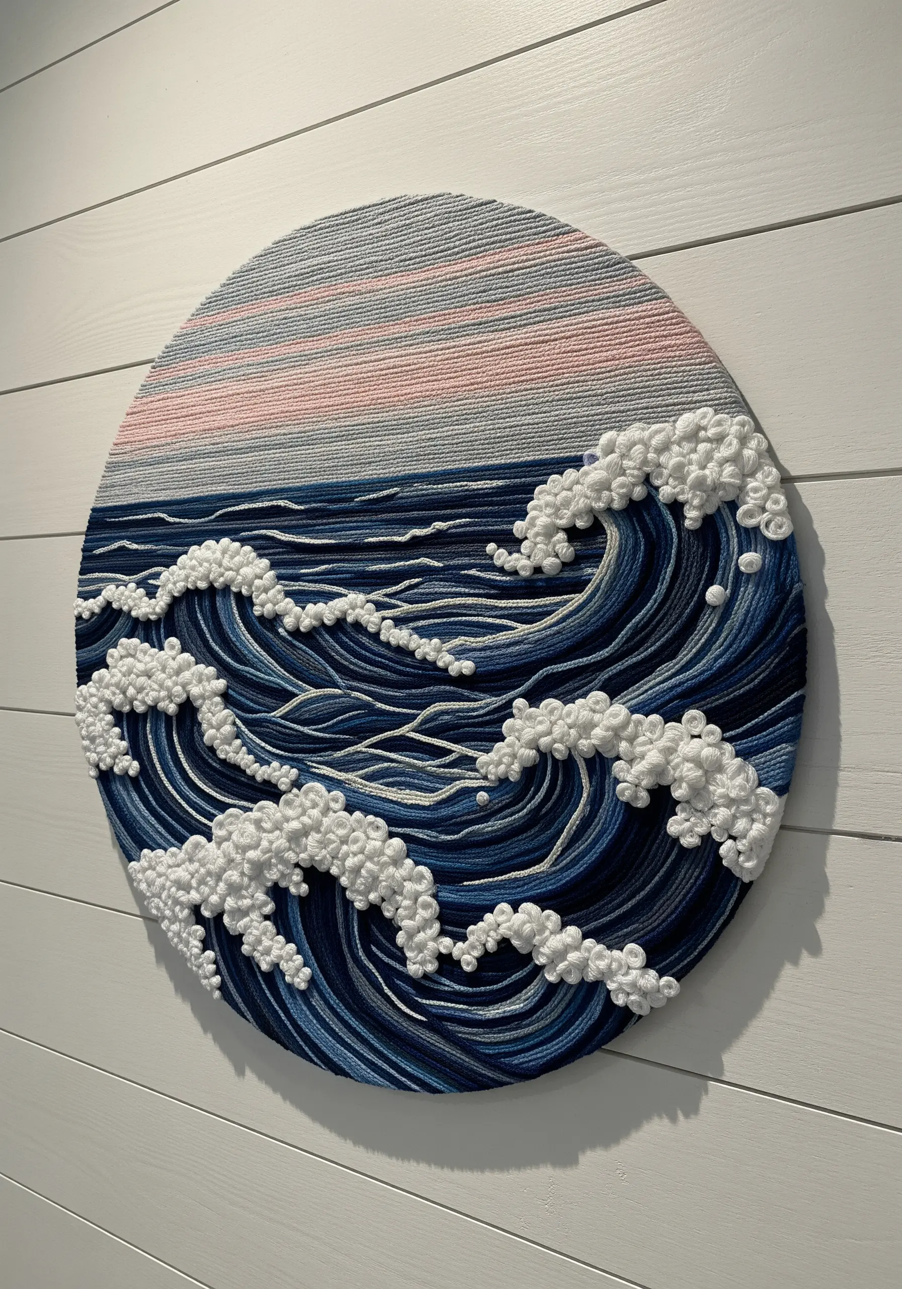 A circular wall art piece depicting deep blue ocean waves with textured white foam.