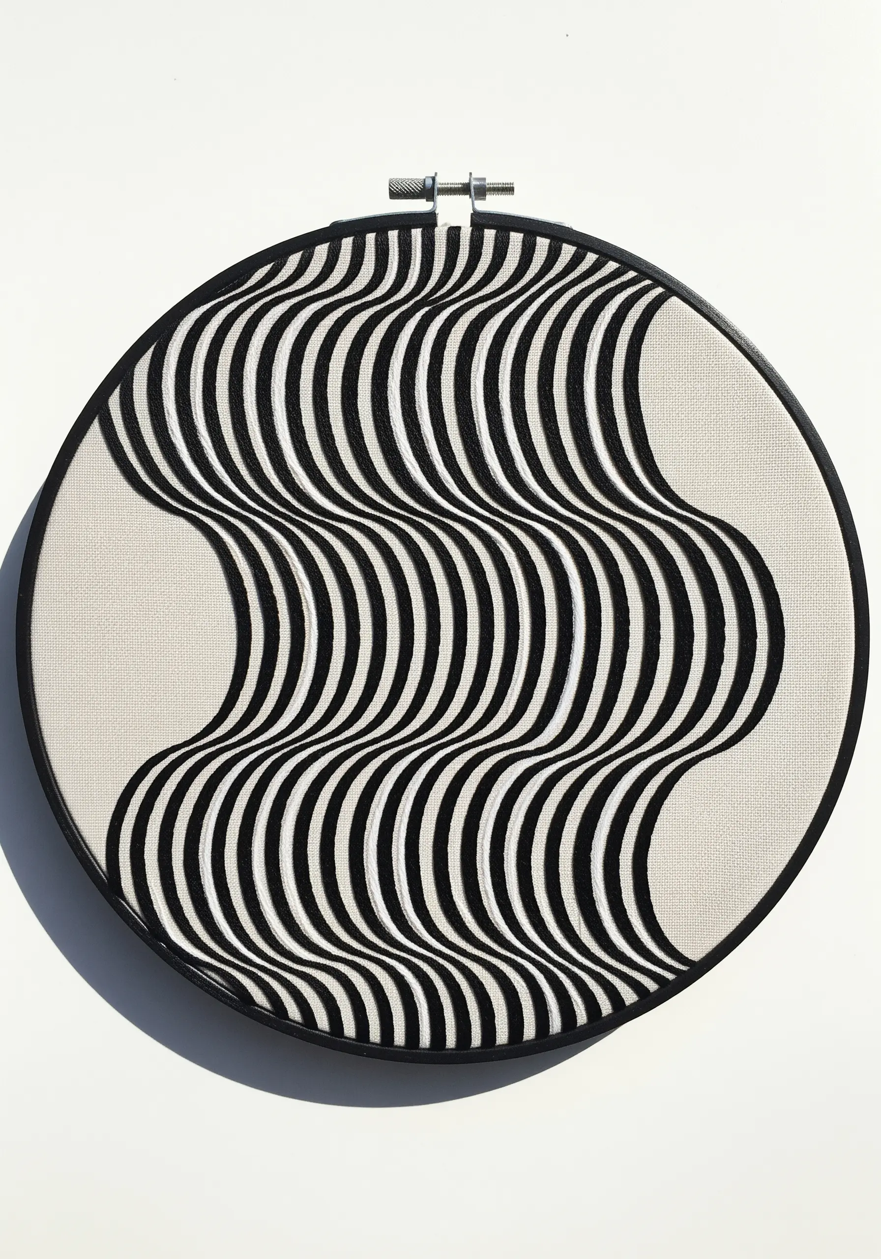 Abstract embroidery of black and white wavy vertical lines creating an optical illusion of movement.