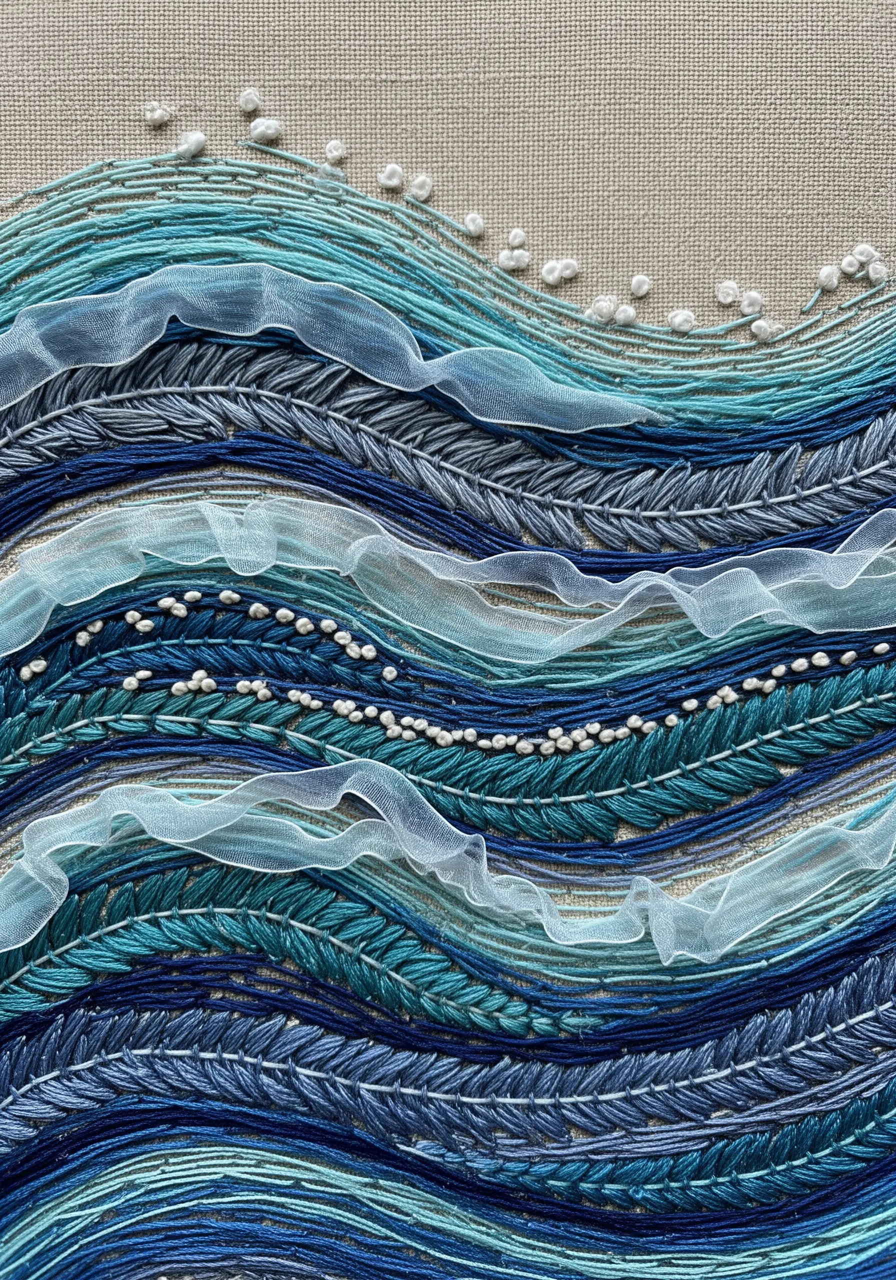Embroidered ocean waves in shades of blue, with sheer ribbon and white French knots for sea foam
