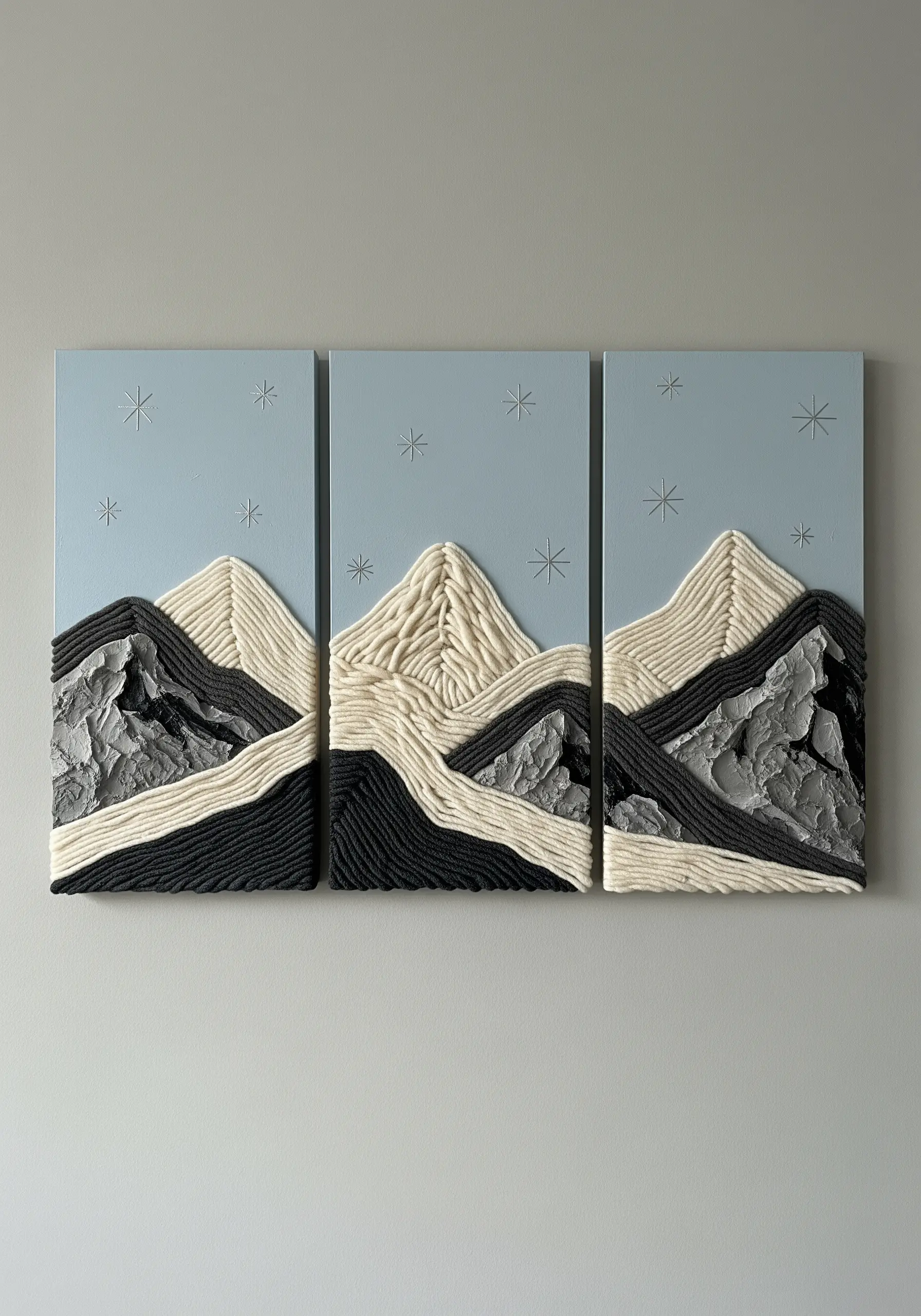A triptych of mountain art made with couched yarn and textured plaster on blue panels.