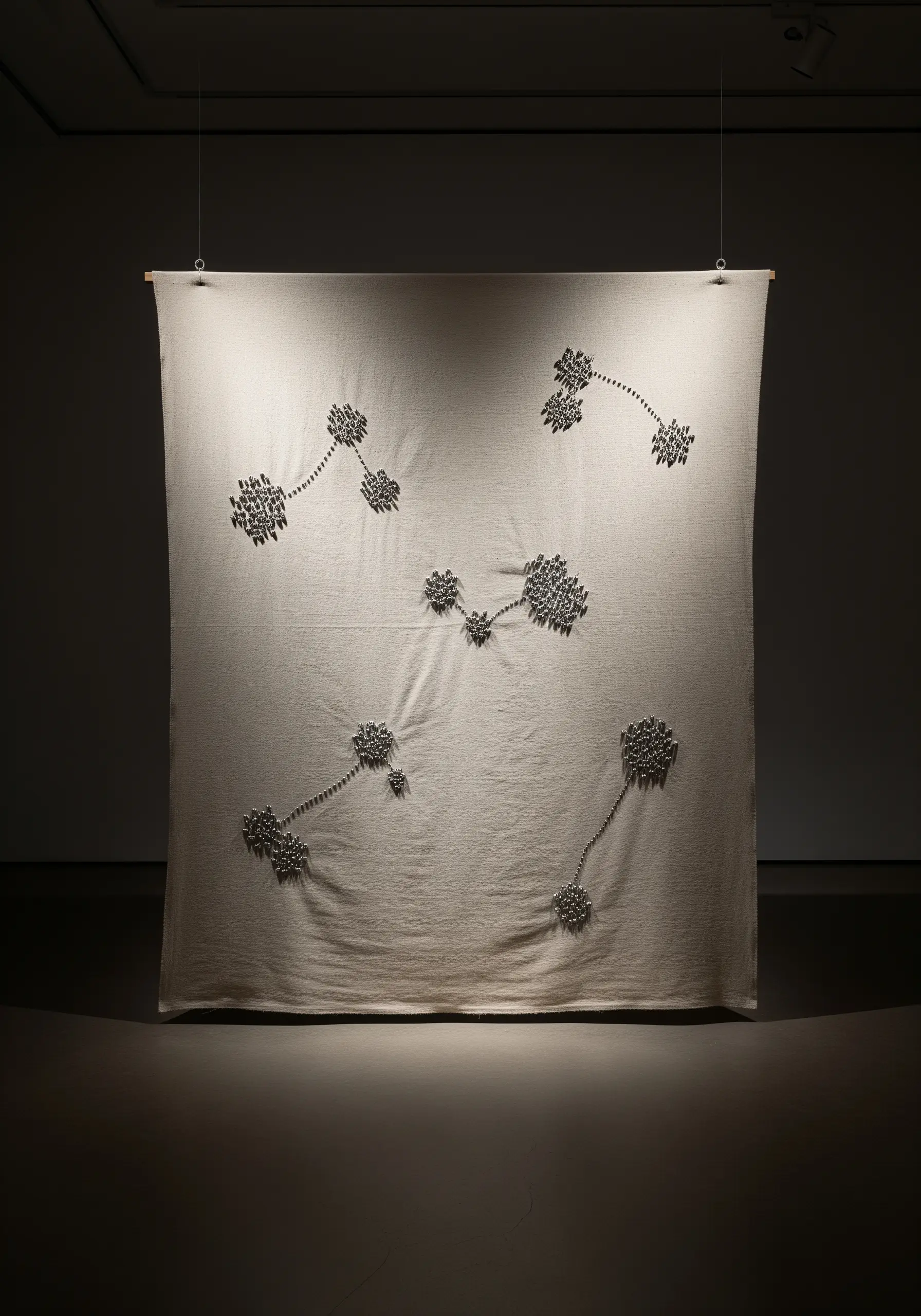 A large fabric wall hanging with dimensional, abstract silver floral clusters.
