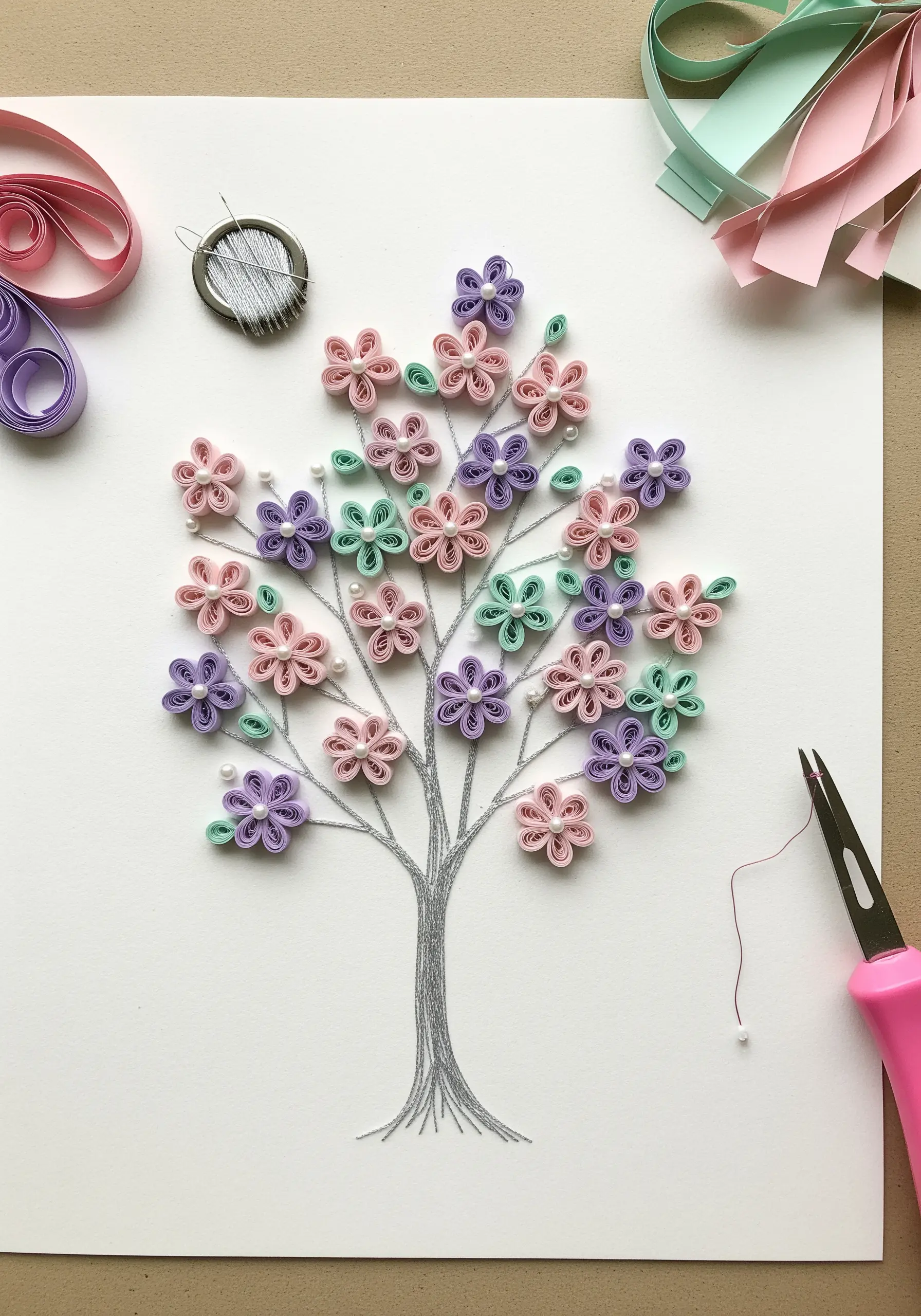 Quilled paper flowers in pastel shades with silver thread stems and pearl details.