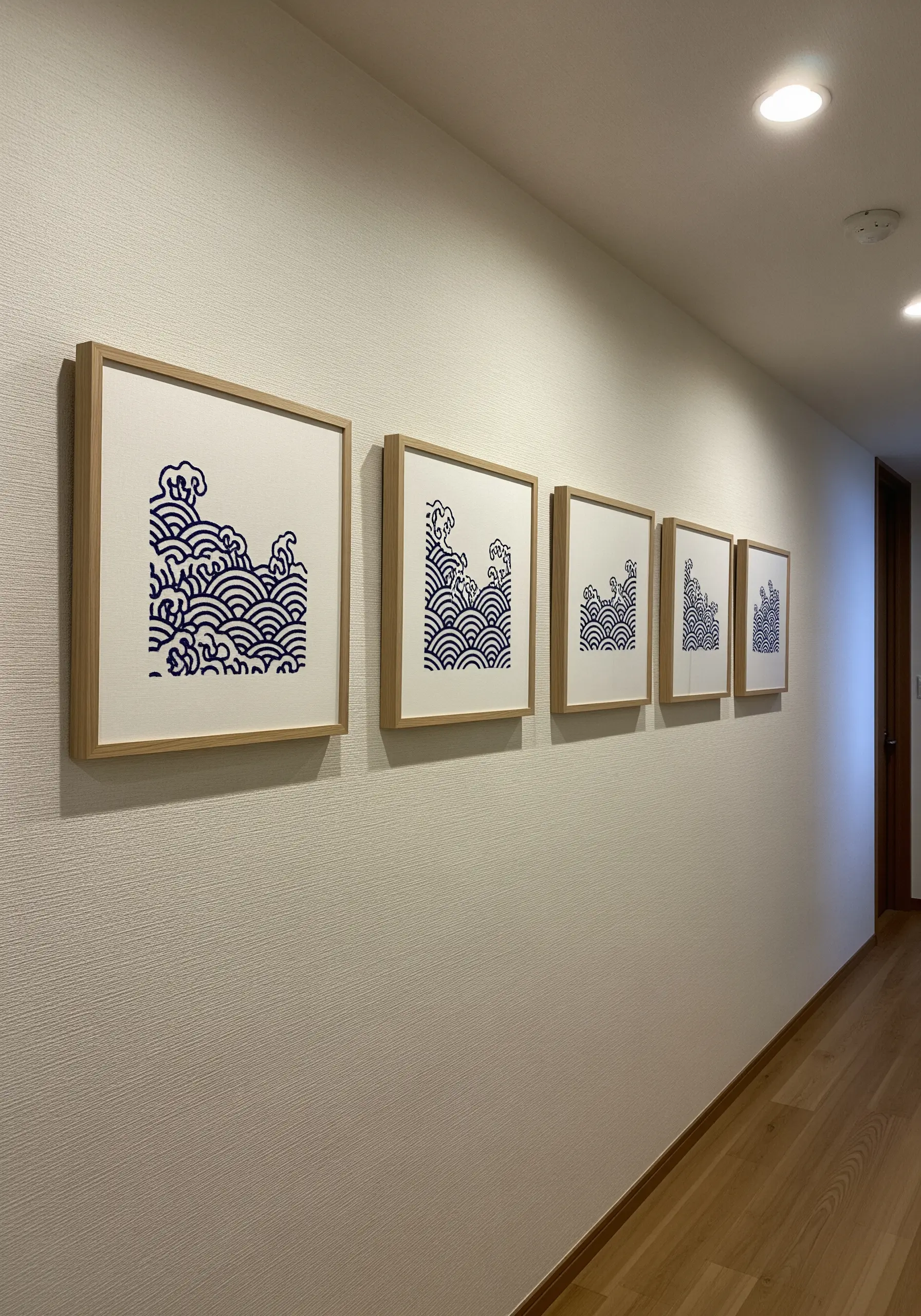 A series of five framed embroideries showing a shrinking Japanese wave pattern.