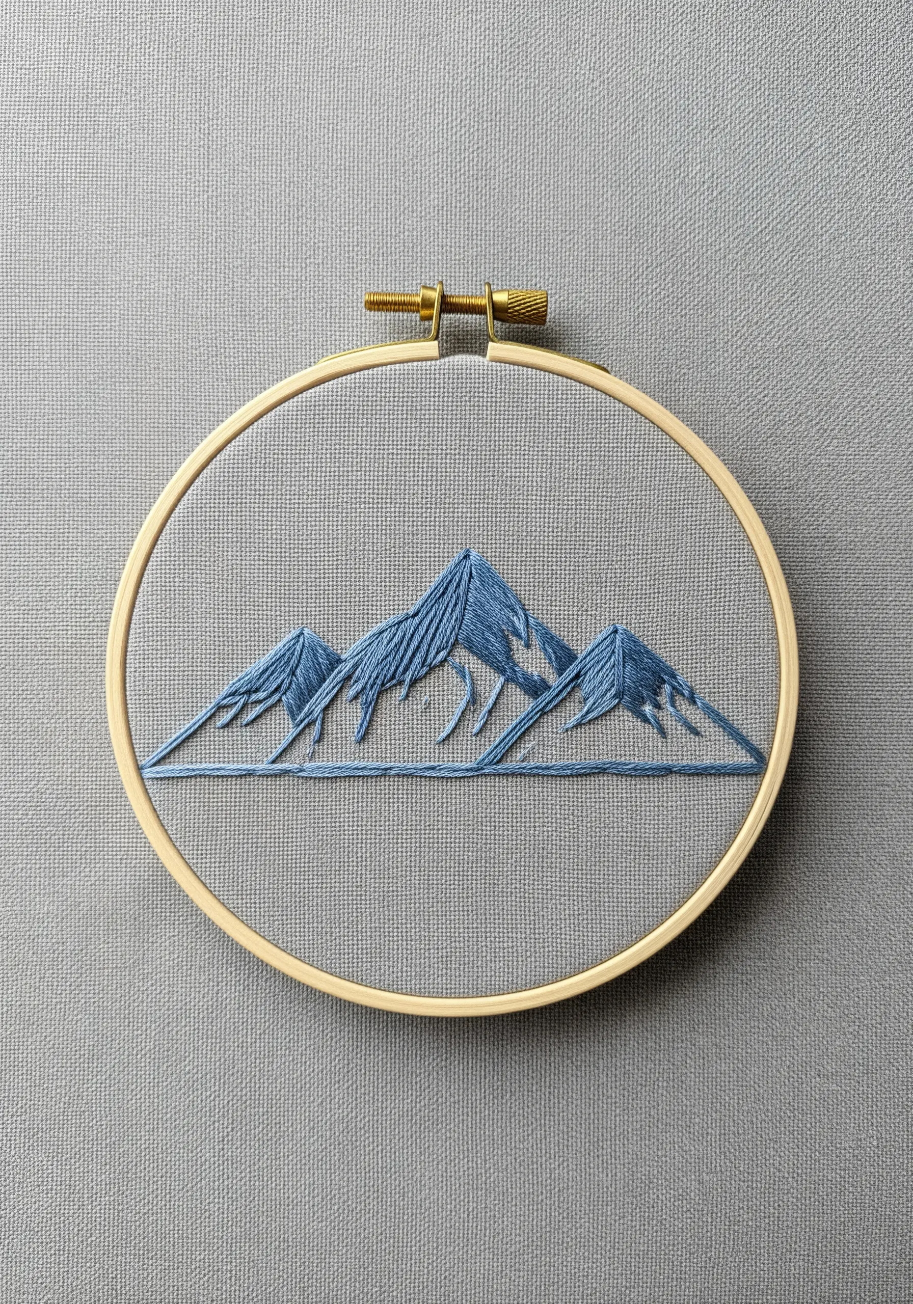 Minimalist mountain range with long-and-short stitch shading in blue tones.