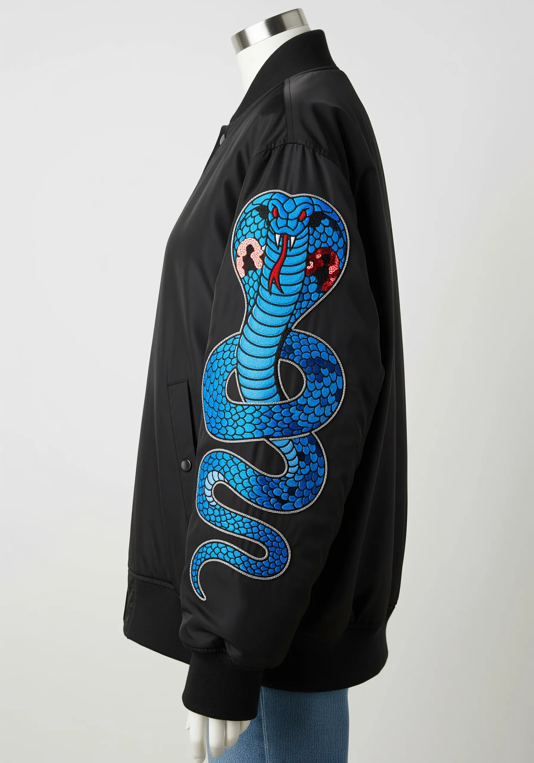 Large embroidered cobra snake on the sleeve of a bomber jacket with sequin details.