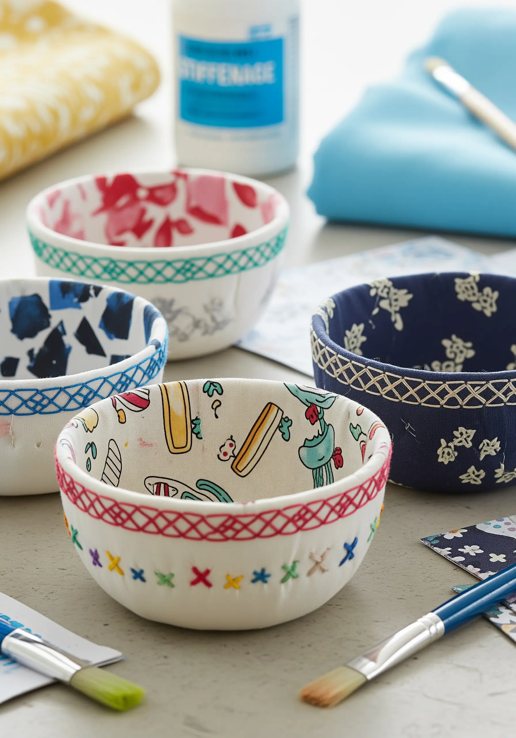Small decorative bowls made from hardened, patterned fabric with embroidered rims.