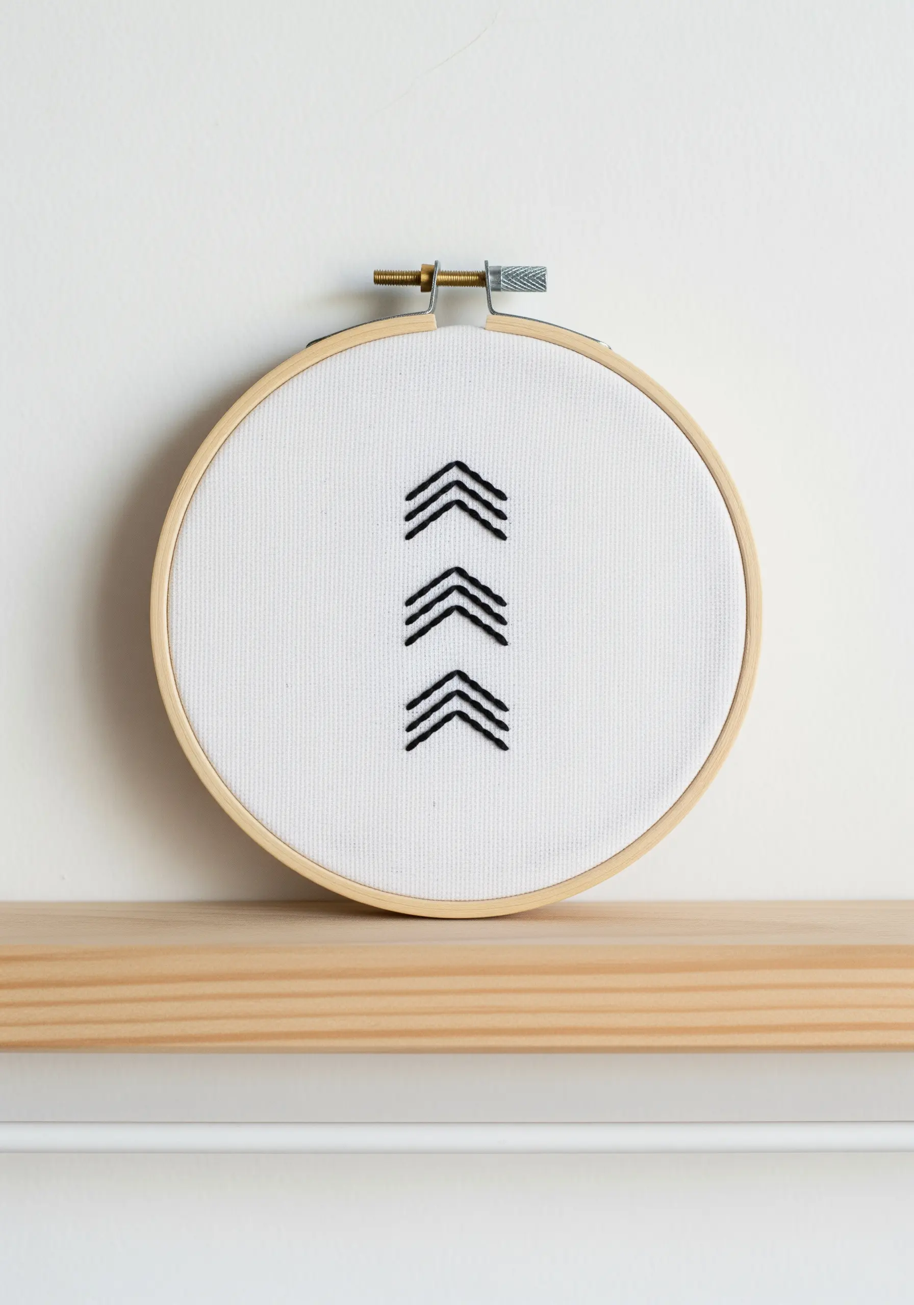 Three sets of stacked black chevrons stitched on white fabric.