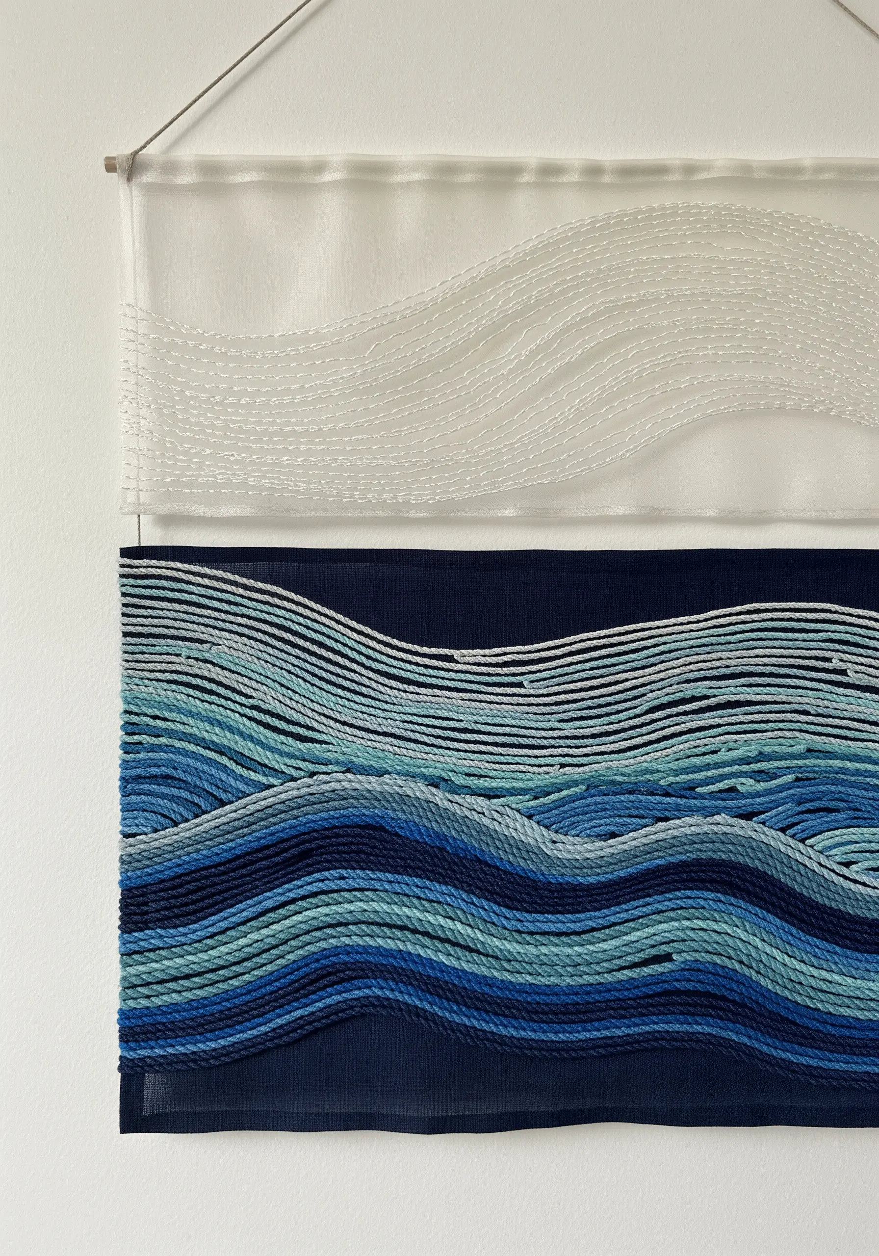 Abstract ocean waves stitched on layers of dark blue and sheer white fabric.