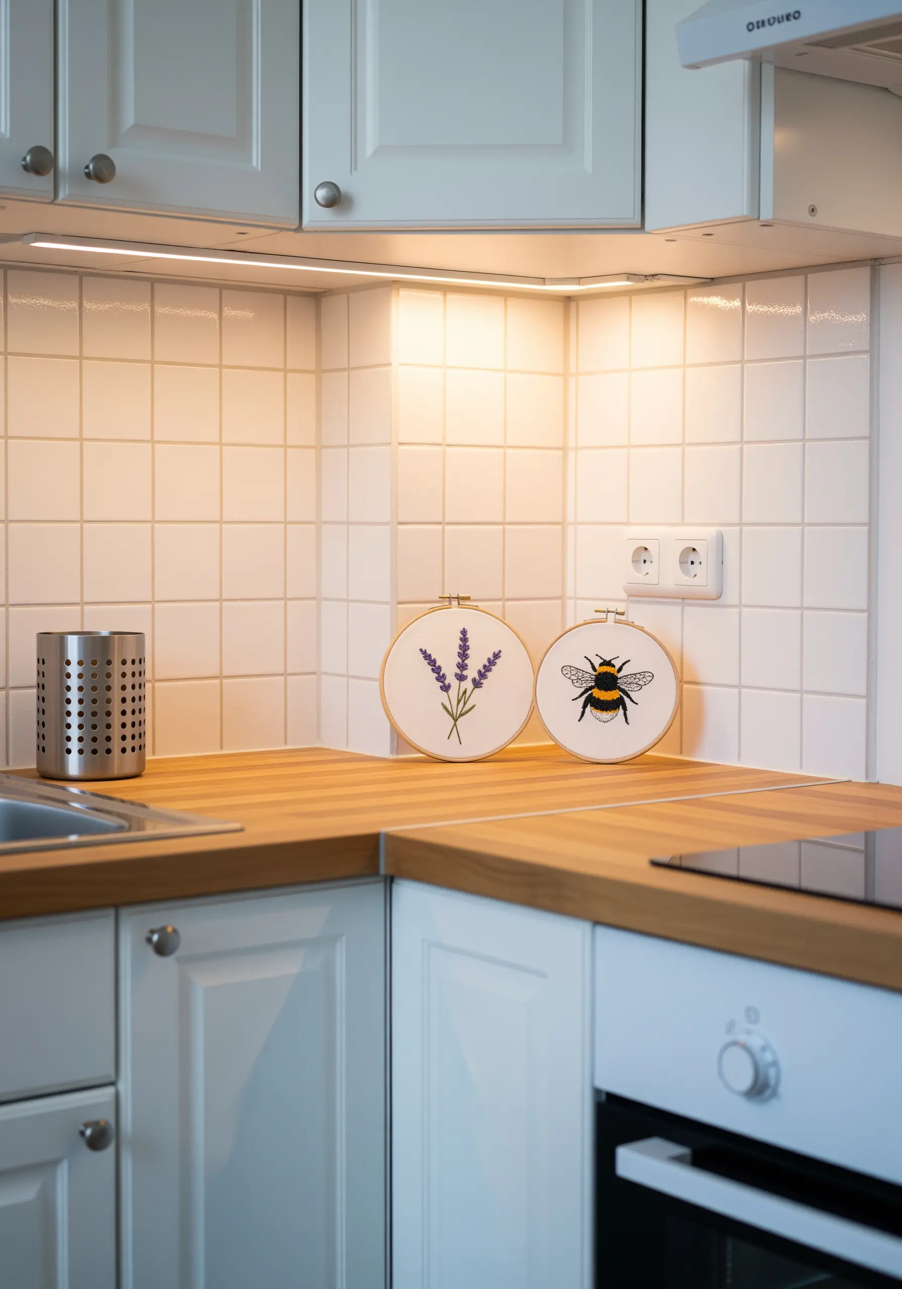 Two embroidery hoops, one with lavender and one with a bee, on a kitchen countertop.