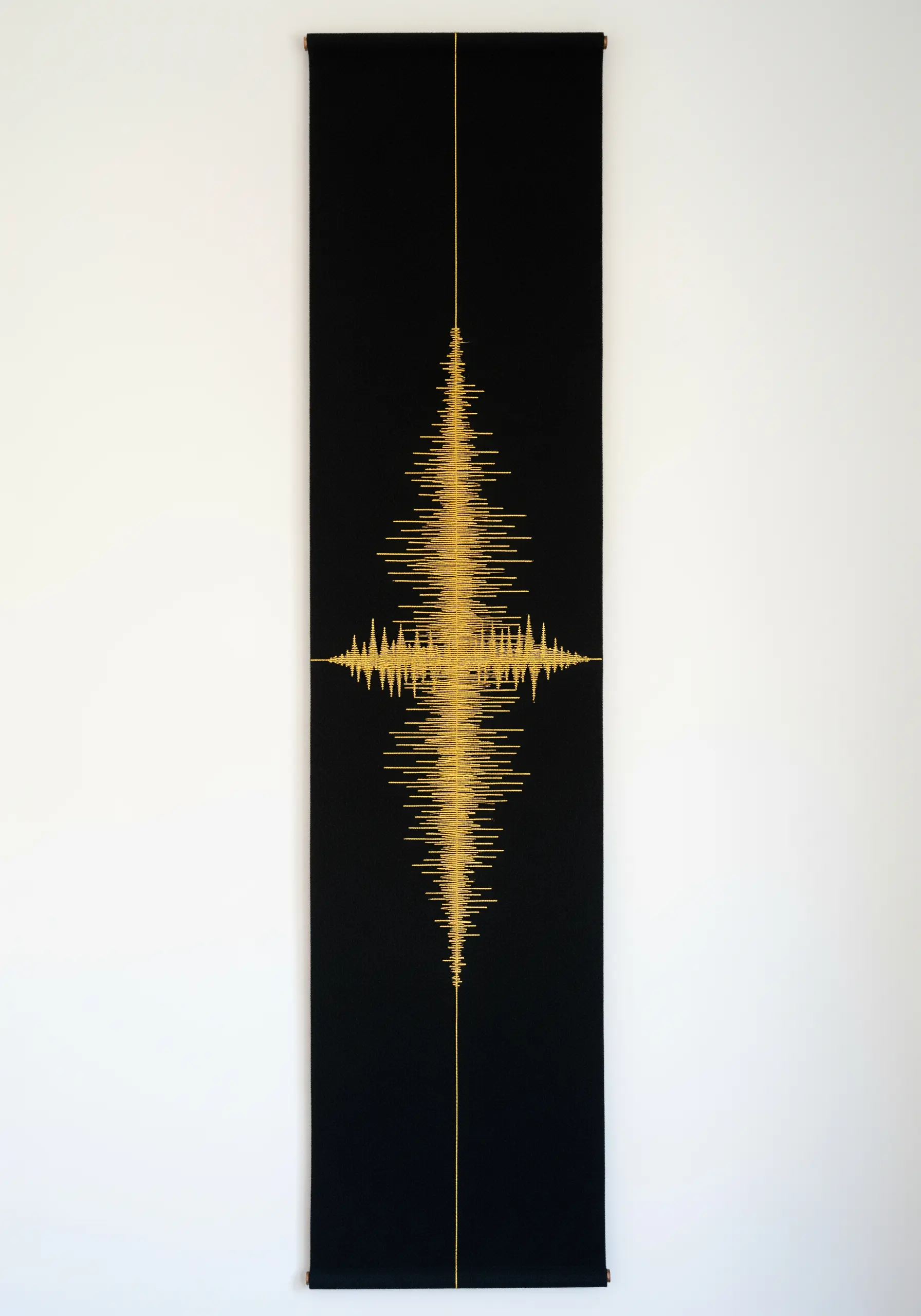 A long black wall hanging with a gold soundwave embroidered down the center.