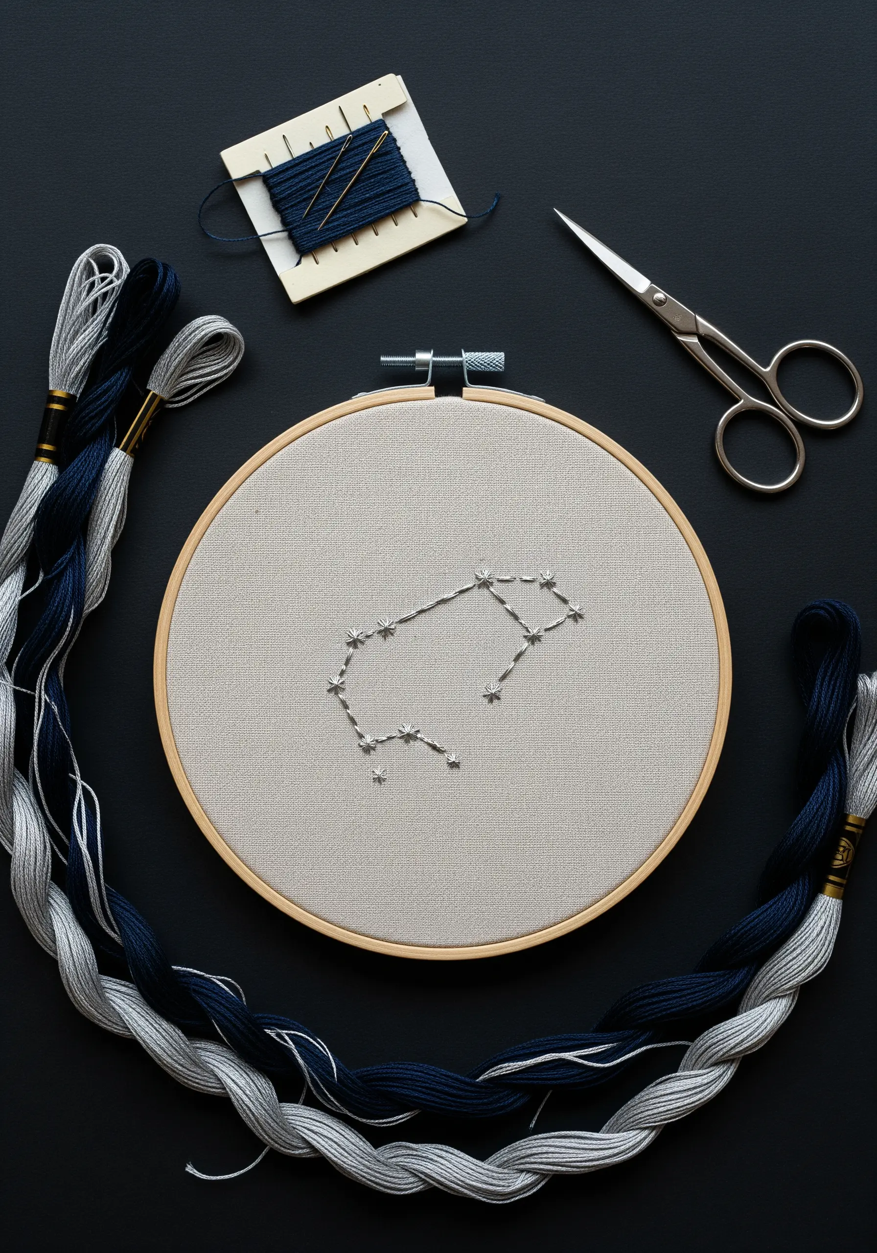 Aquarius constellation stitched with silver thread in an embroidery hoop on grey fabric.